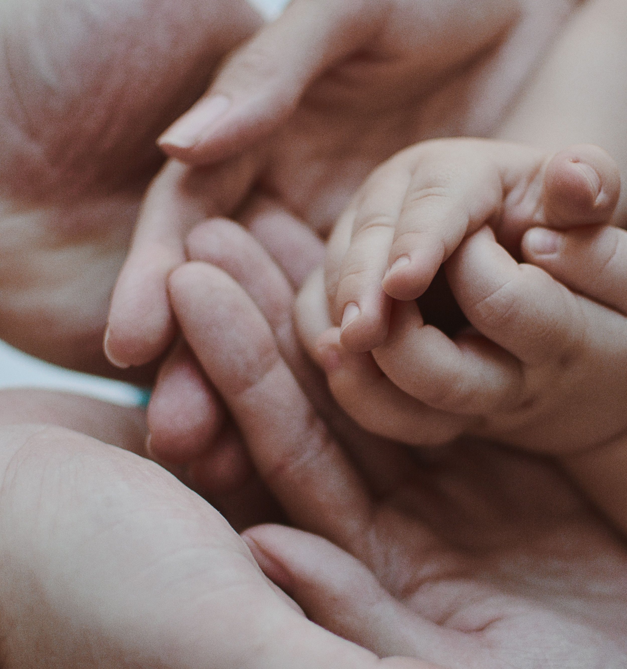 Close-up of a person's hand gently holding a small child's finger, emphasizing the tenderness of the moment.