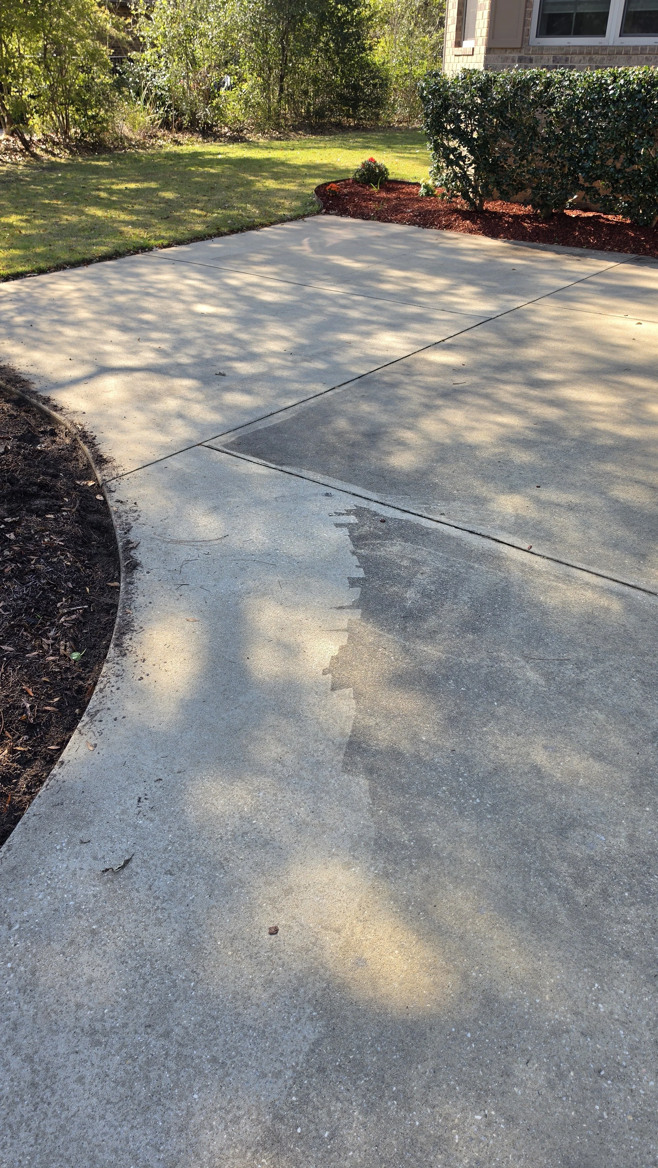 Residential driveway pressure washing services. Clean concrete entrance for a home in the Pensacola area, free of dirt and mold.