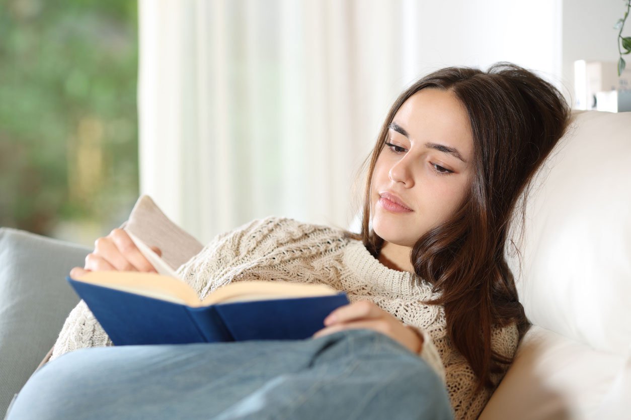 Teen relaxing with a book, representing support for anxiety, stress, emotional overwhelm, and the pressures teens face today.