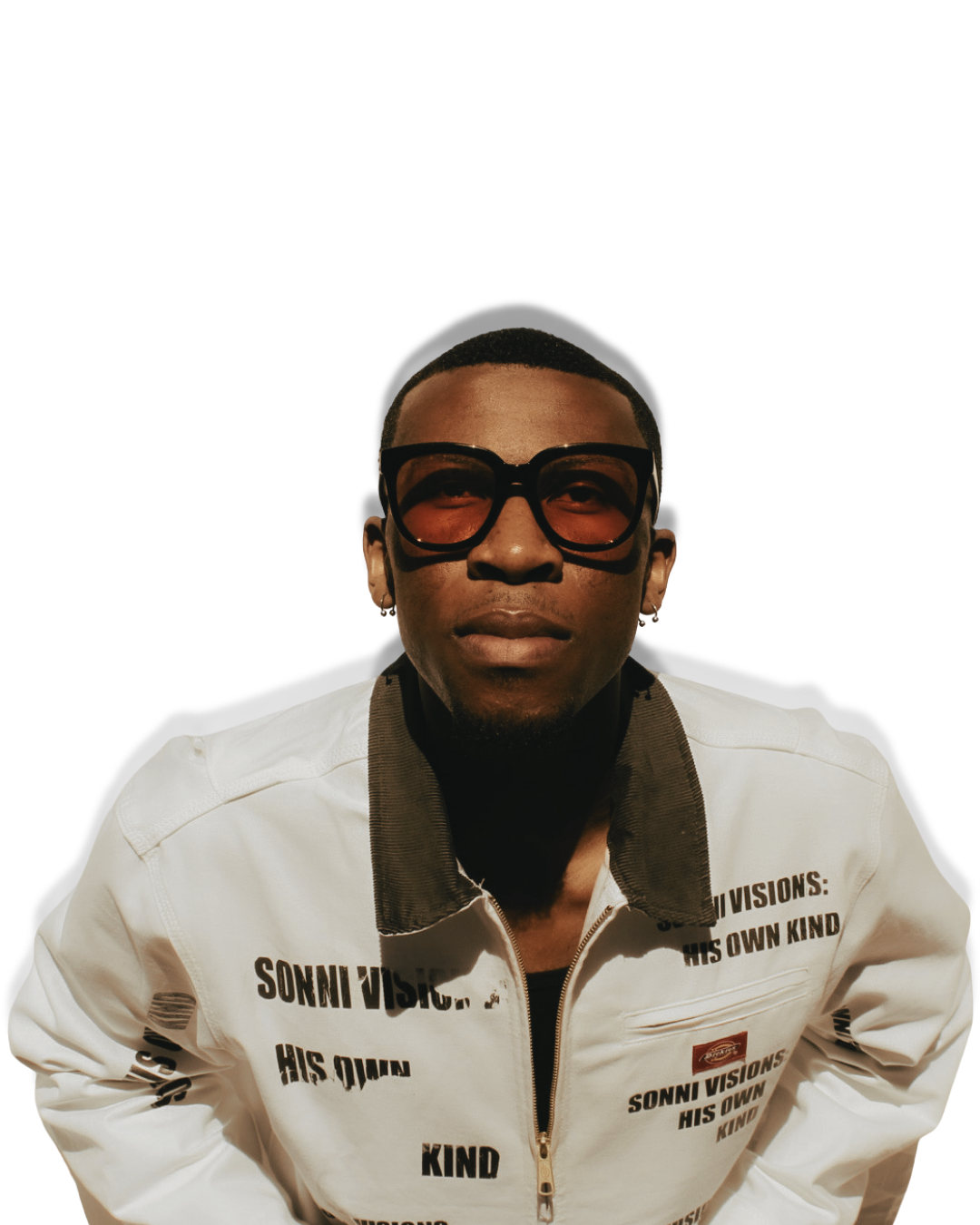 A young man with short hair and dark skin wearing large black sunglasses, a white jacket with black text, and a black turtleneck underneath.