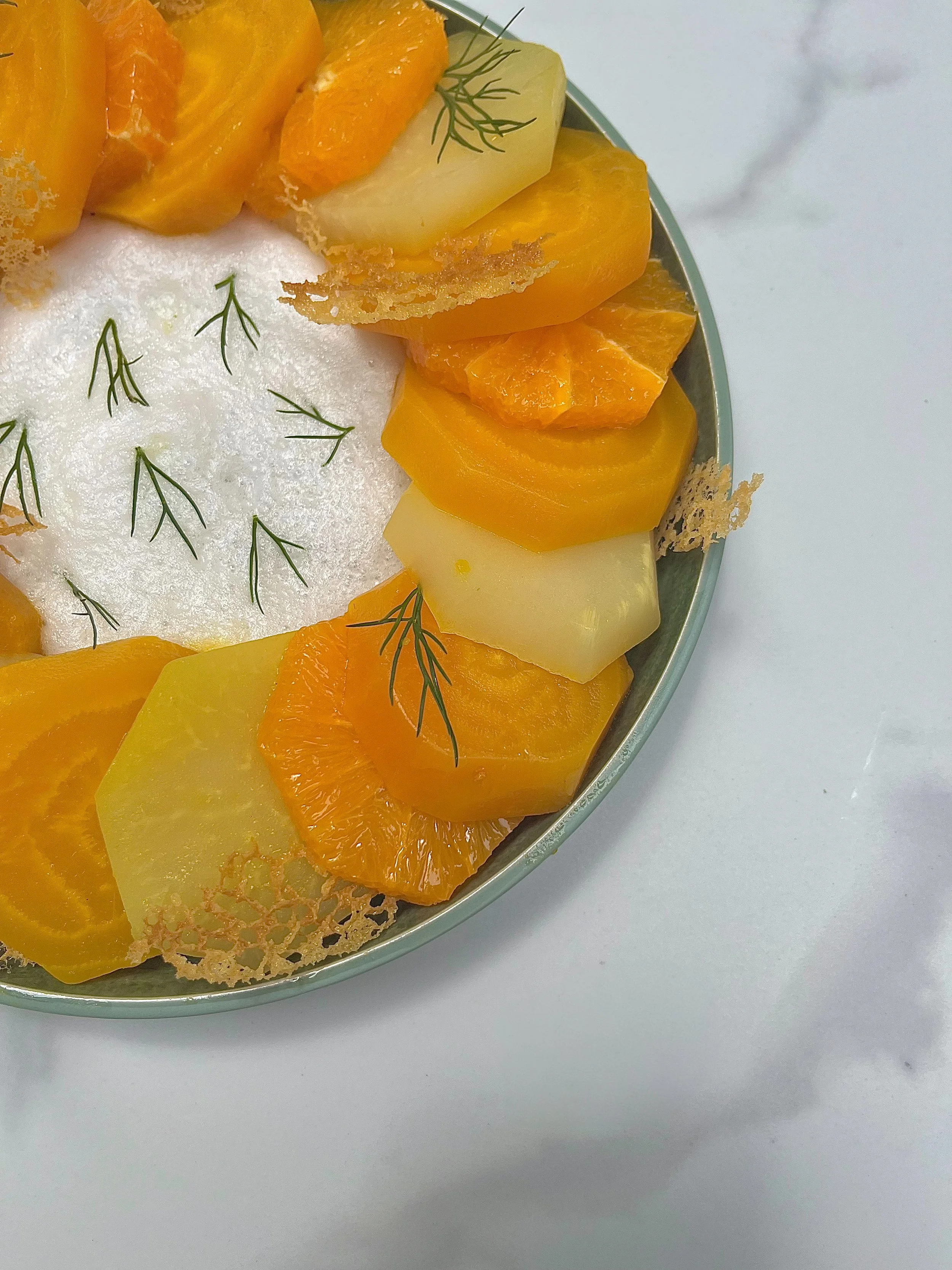 Close-up of a decorative fruit platter with slices of orange, pineapple, and yellow melon garnished with small green herbs on a white surface.