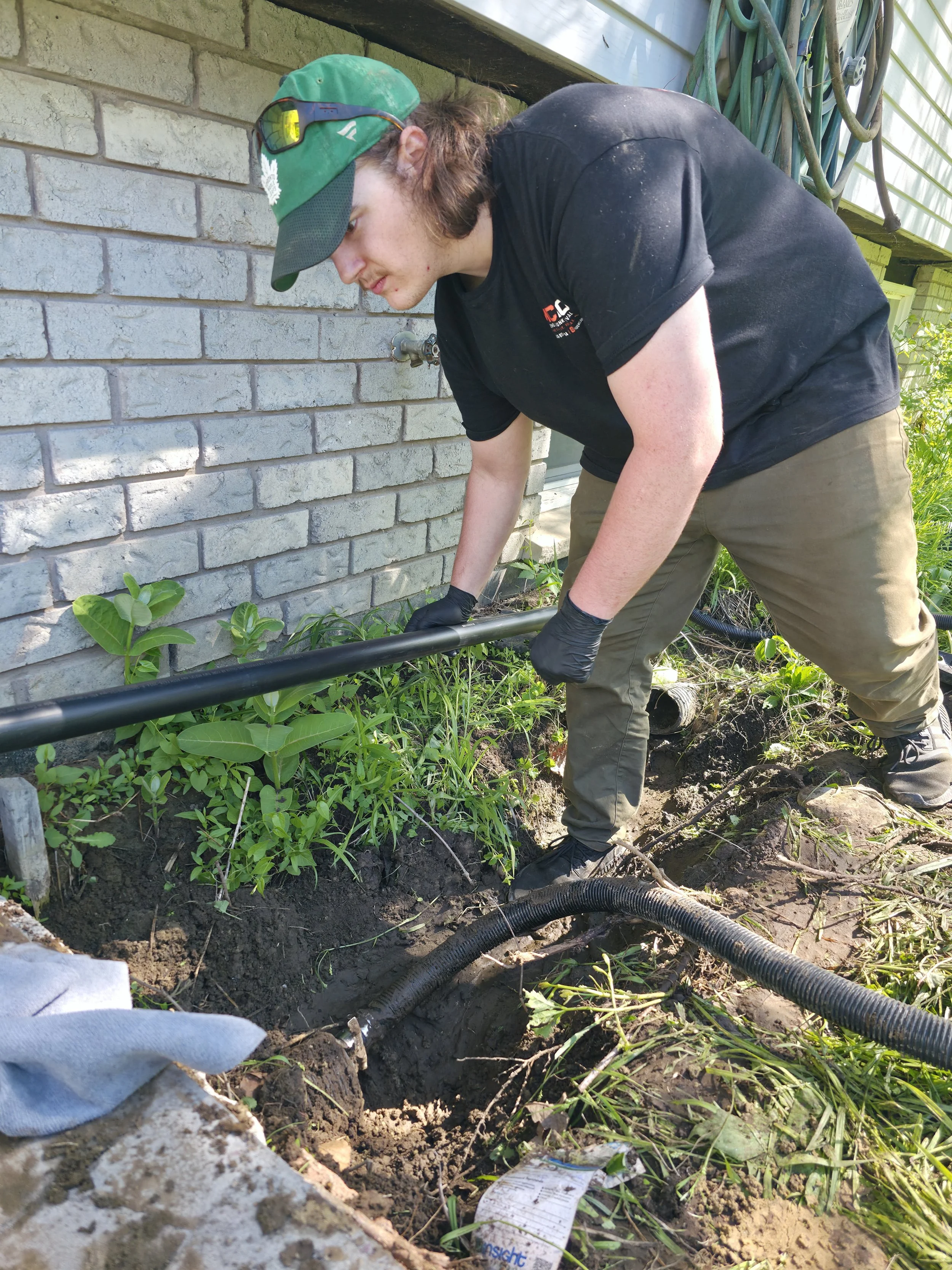 McMo Demo & Junk Removal installing a residential drainage system and buried discharge line to help protect a home's foundation from water damage.
