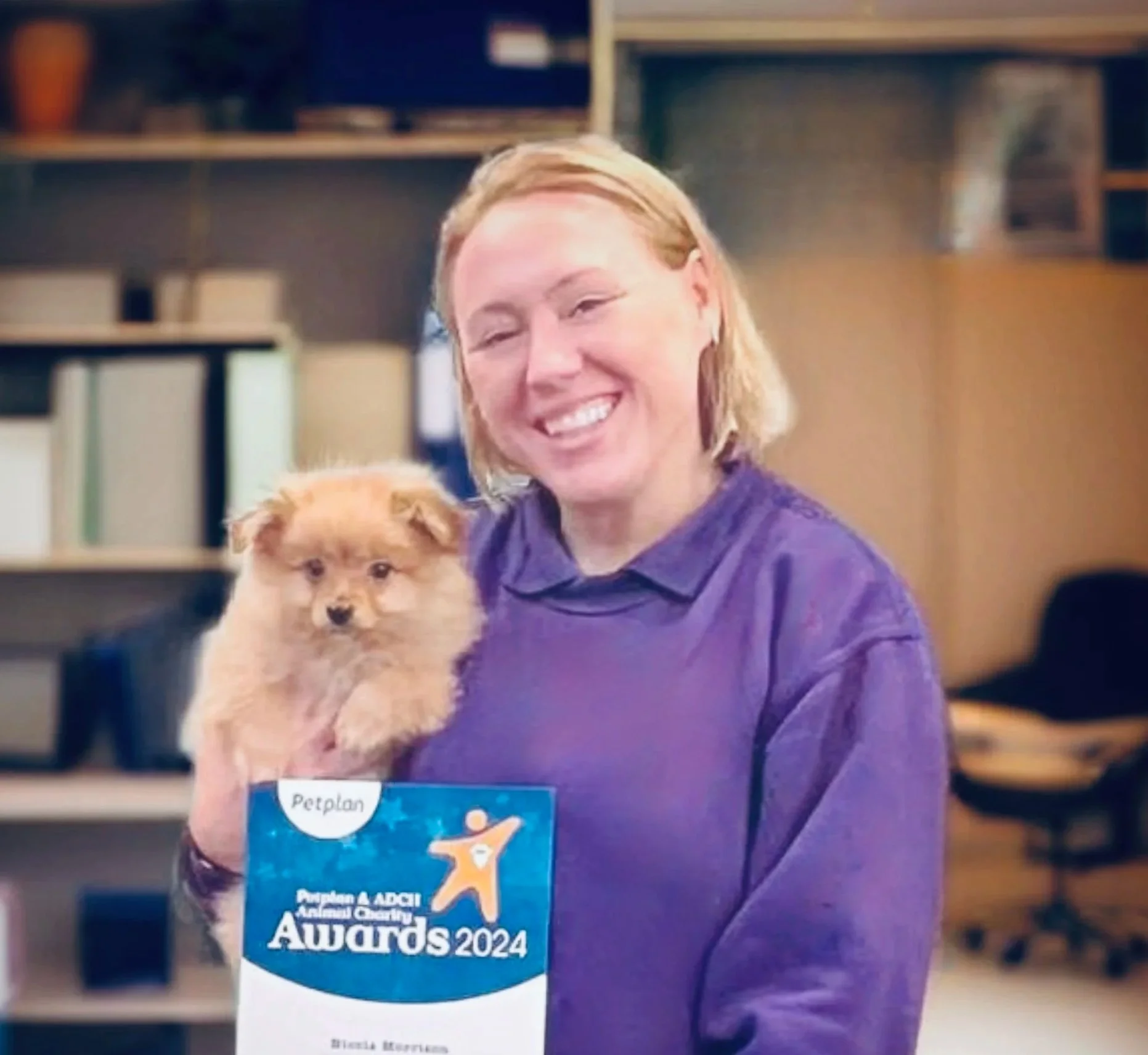 Nikki Morrison smiling, holding a puppy and a Petplan ADCH Animal Choice Awards Nominee 2024 certificate.