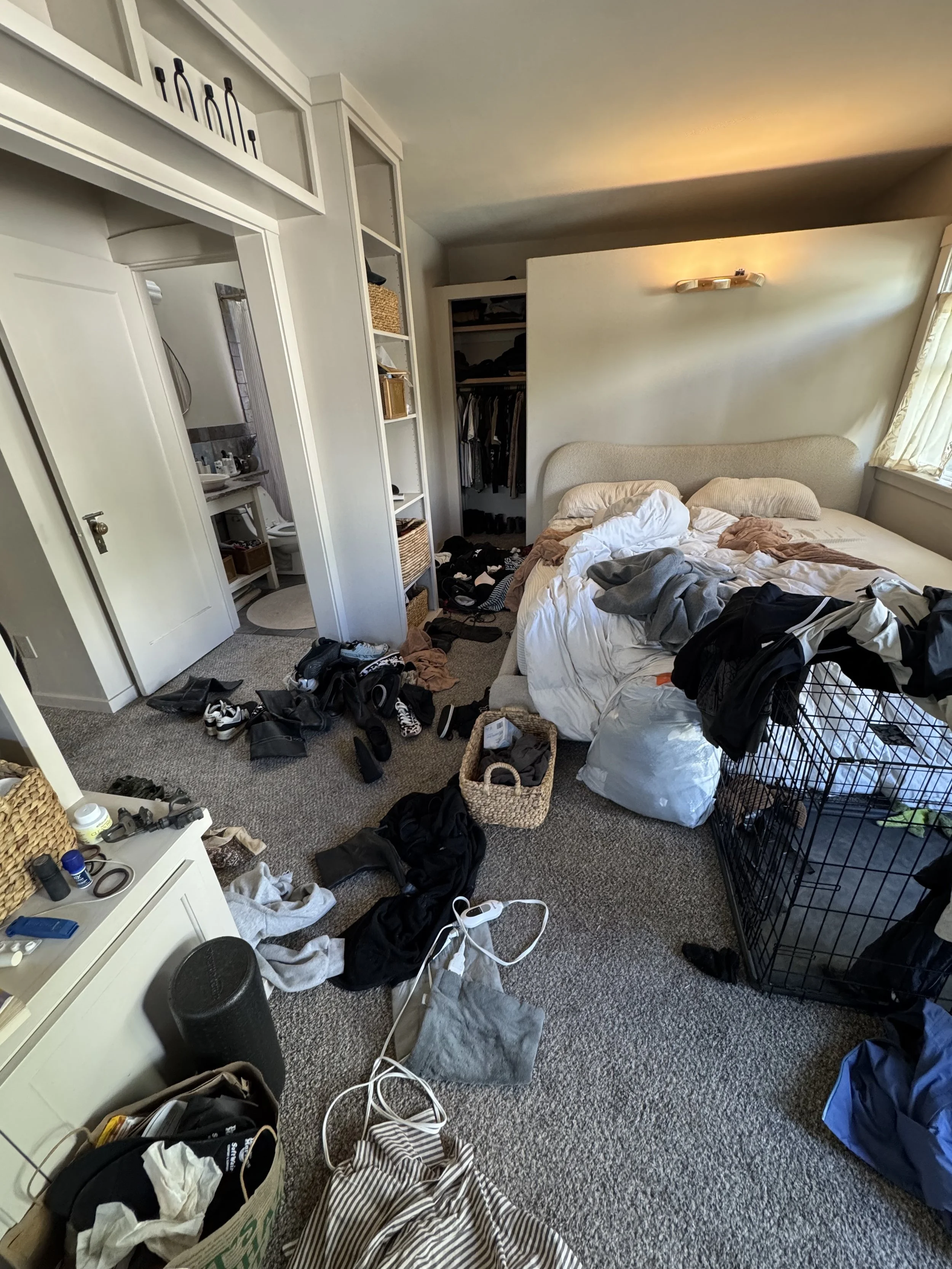 Messy bedroom with a bed, open closet, and cluttered floor with clothes, shoes, and miscellaneous items.