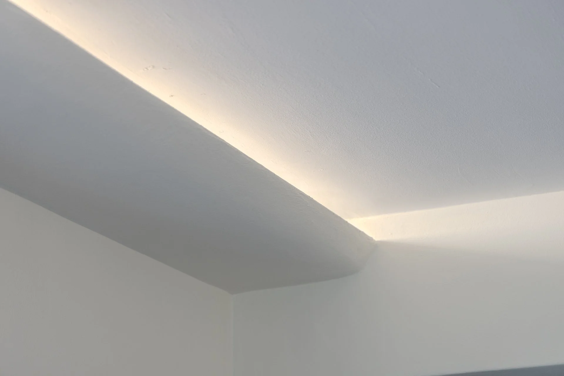 Close-up of a ceiling with recessed lighting creating a soft glow along the edges.