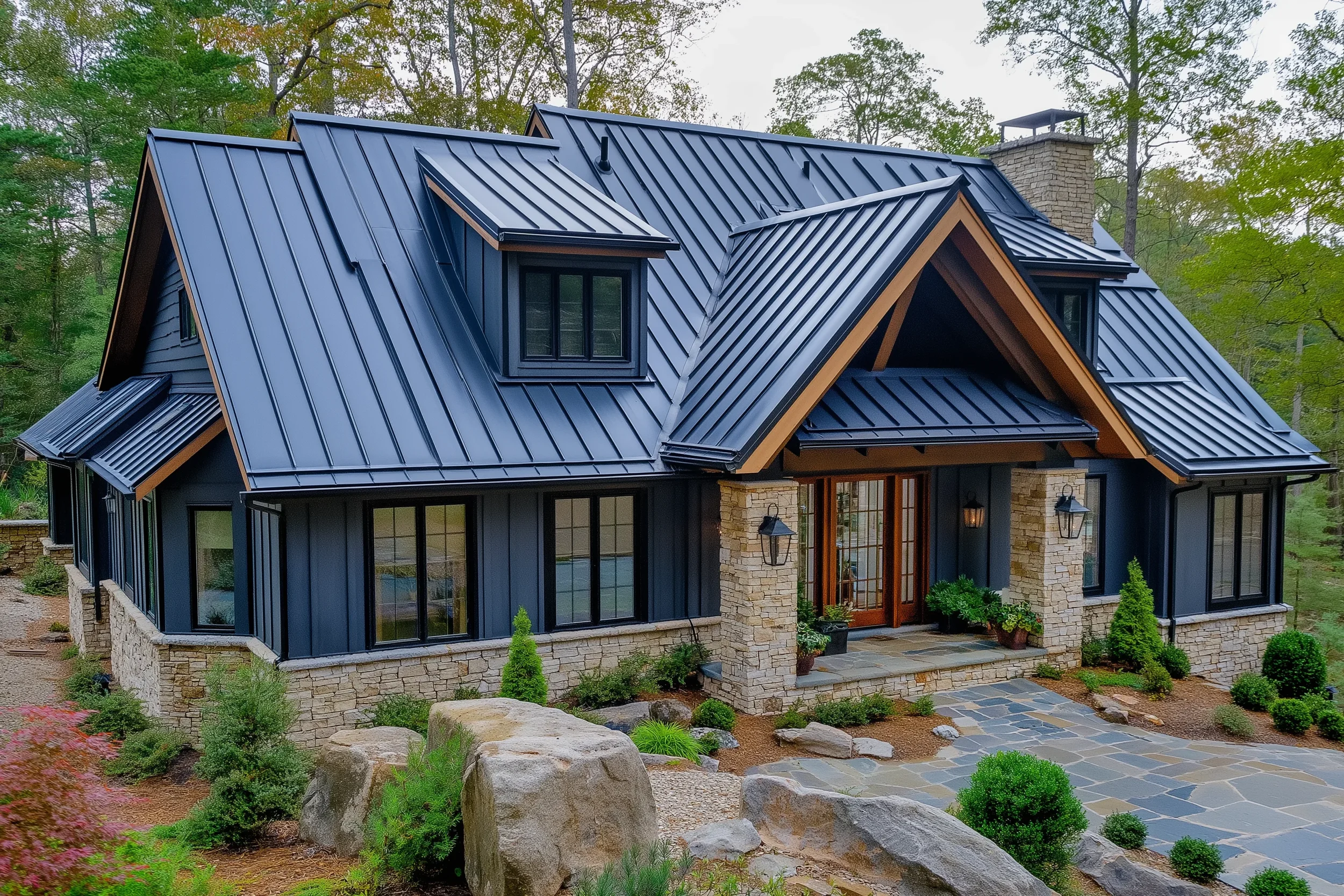 A modern house with black metal roof panels, large windows, and stone accents, surrounded by greenery and landscaped garden.