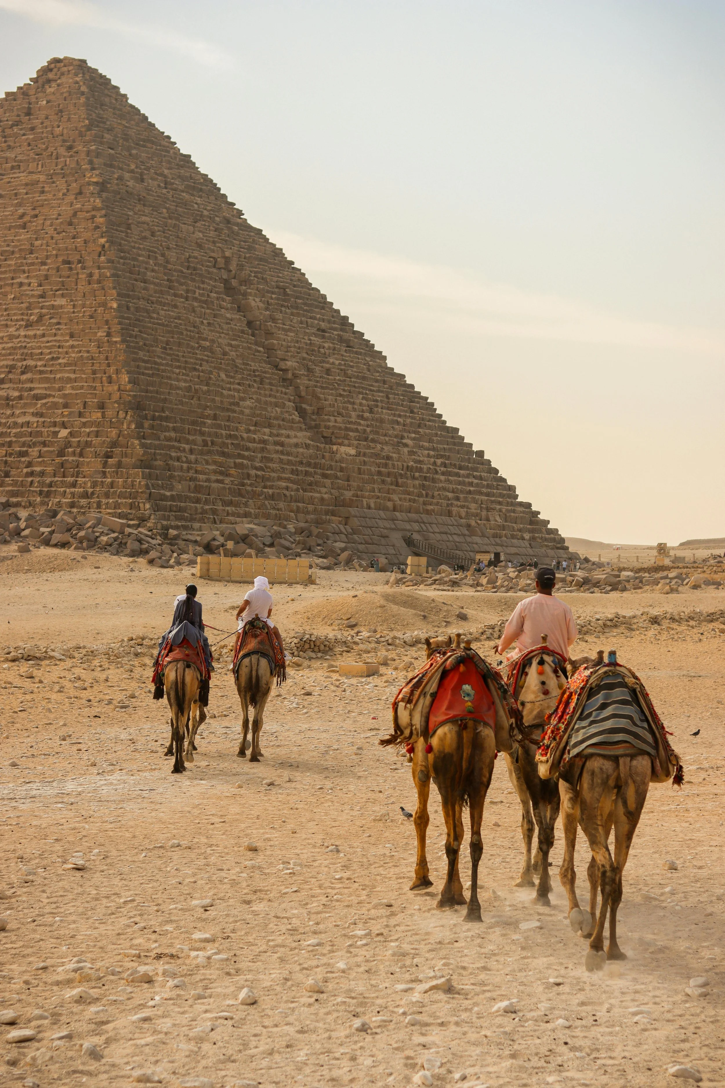 People riding camels in front of the stepped pyramid at the Giza Plateau in Egypt.