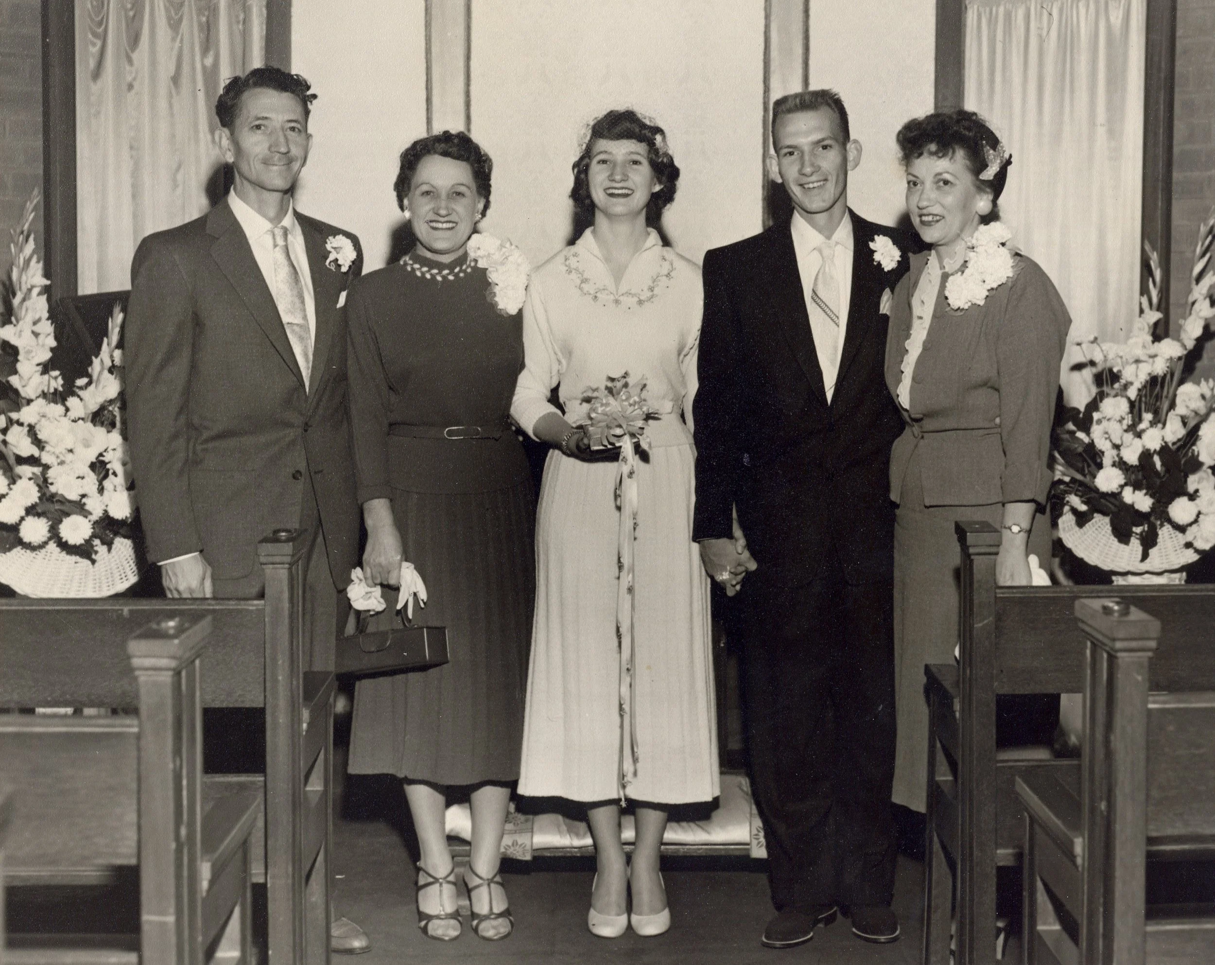 Black and white photo of five people, two women and three men, standing behind a table at a wedding reception. My Mom and Dad's Wedding