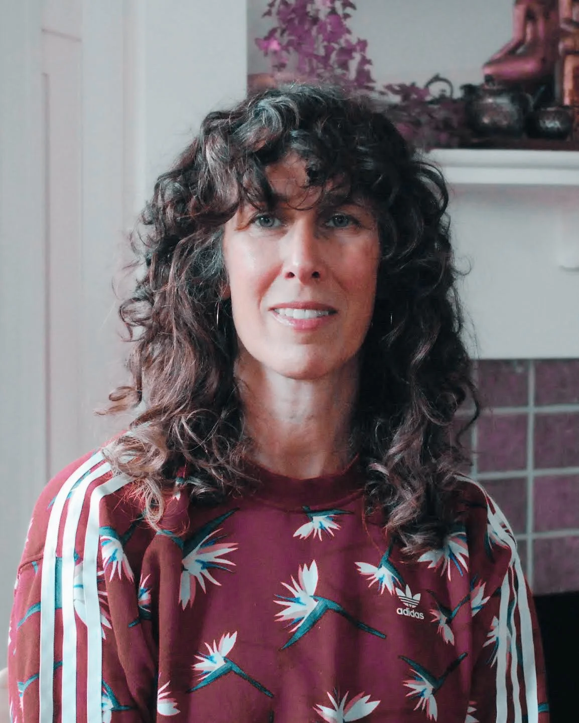Headshot of Hagar Scher wearing a red sweatshirt with birds of paradise pattern.