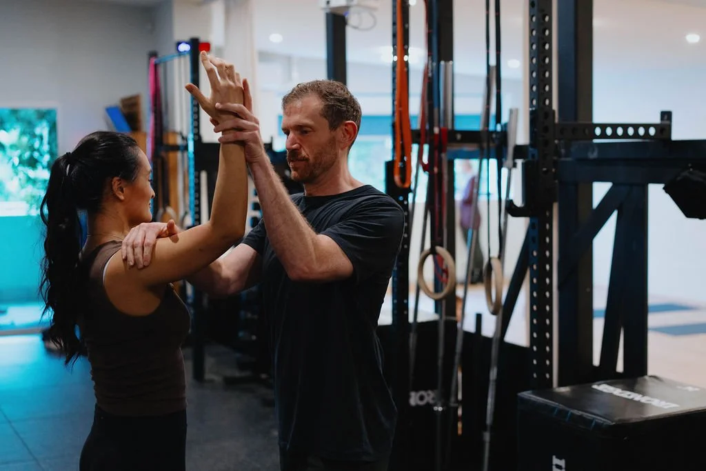 A physiotherapist is helping a client lift her arm up and providing advice