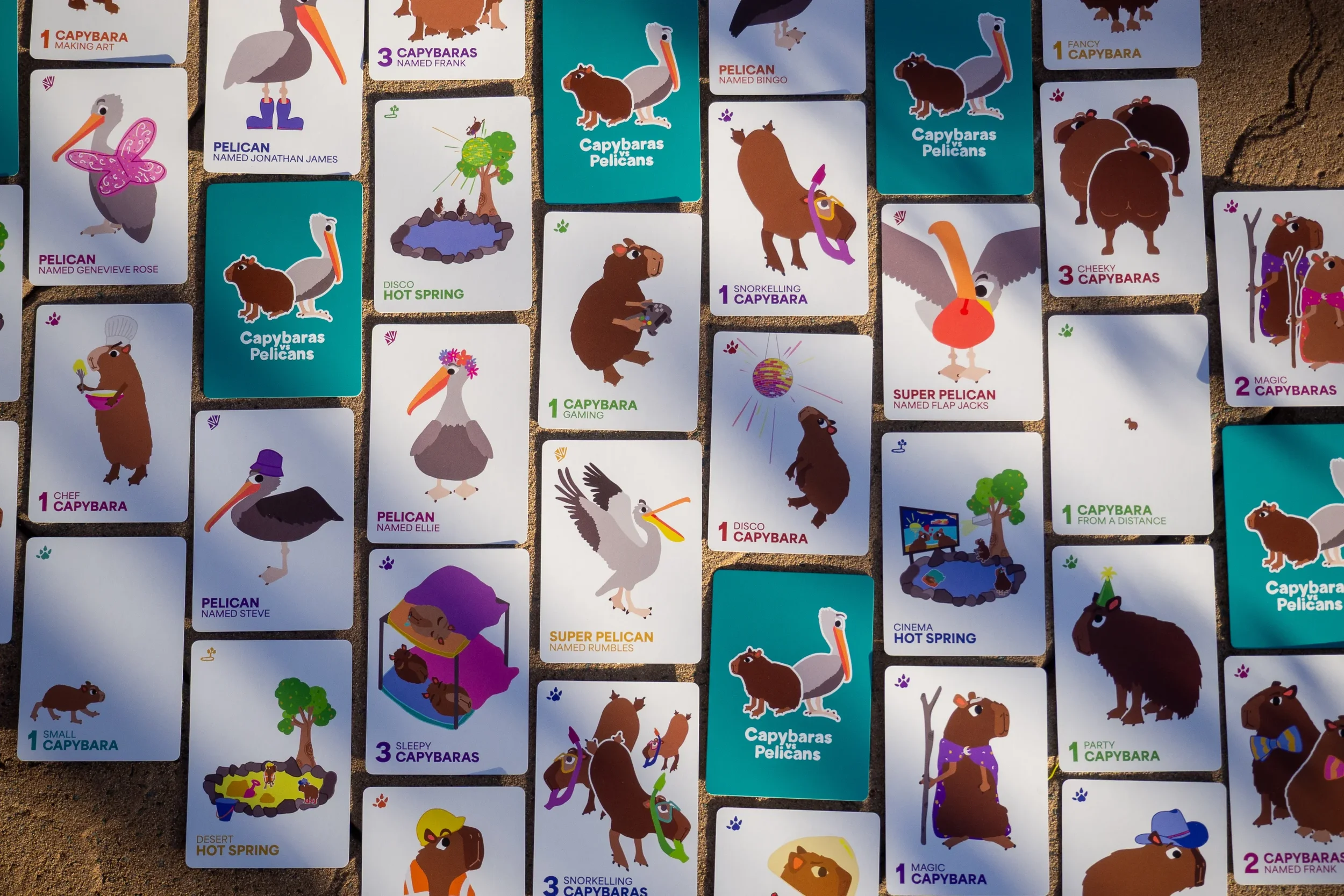 Many playing cards featuring capybaras, pelicans, and hot springs