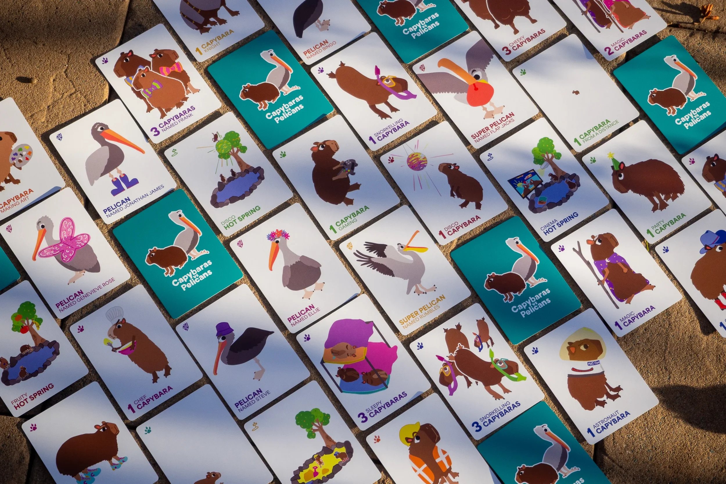 Many playing cards depicting capybaras, pelicans, and hot springs