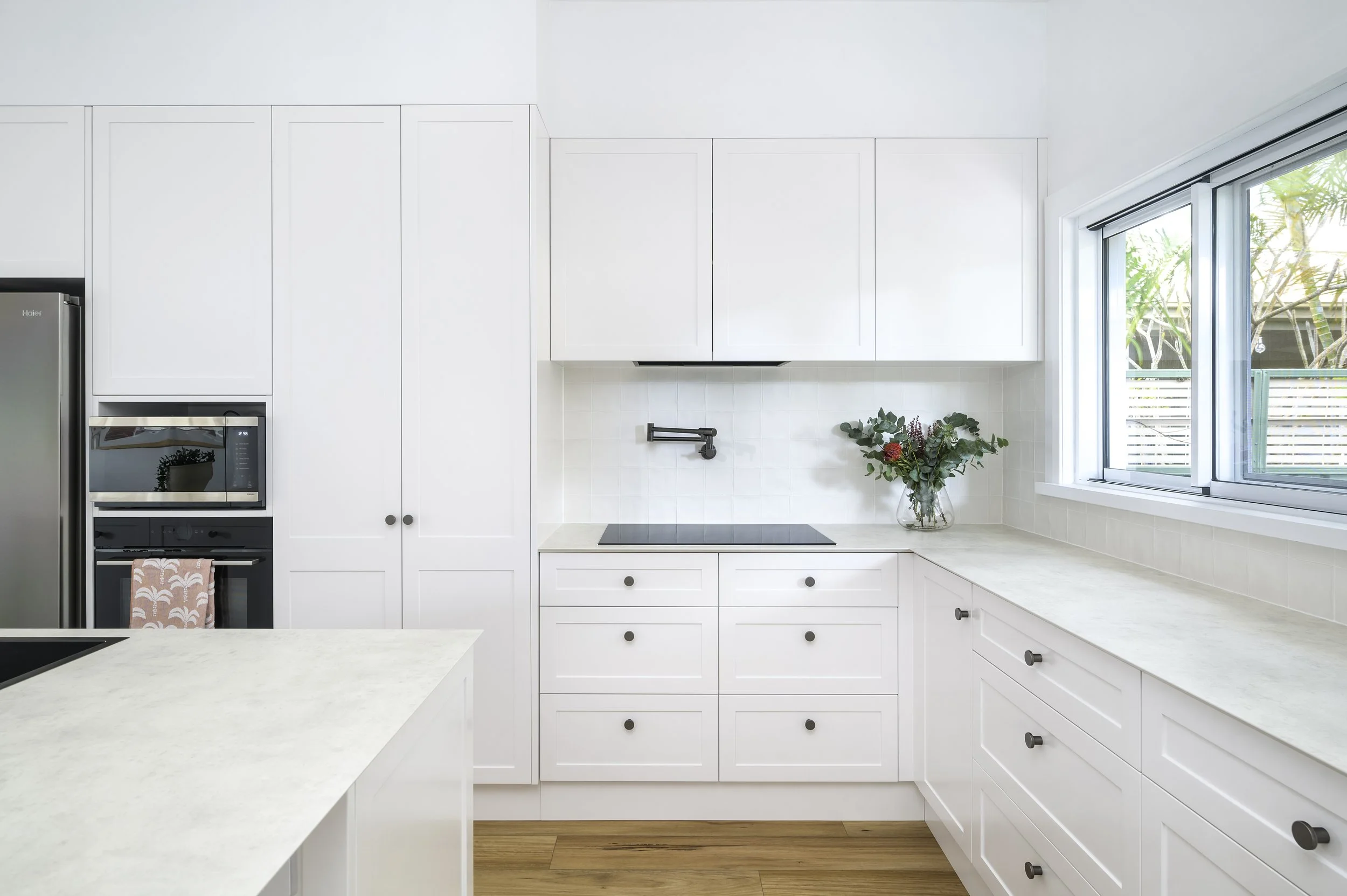 Modern white kitchen with pot filler and shaker cabinetry