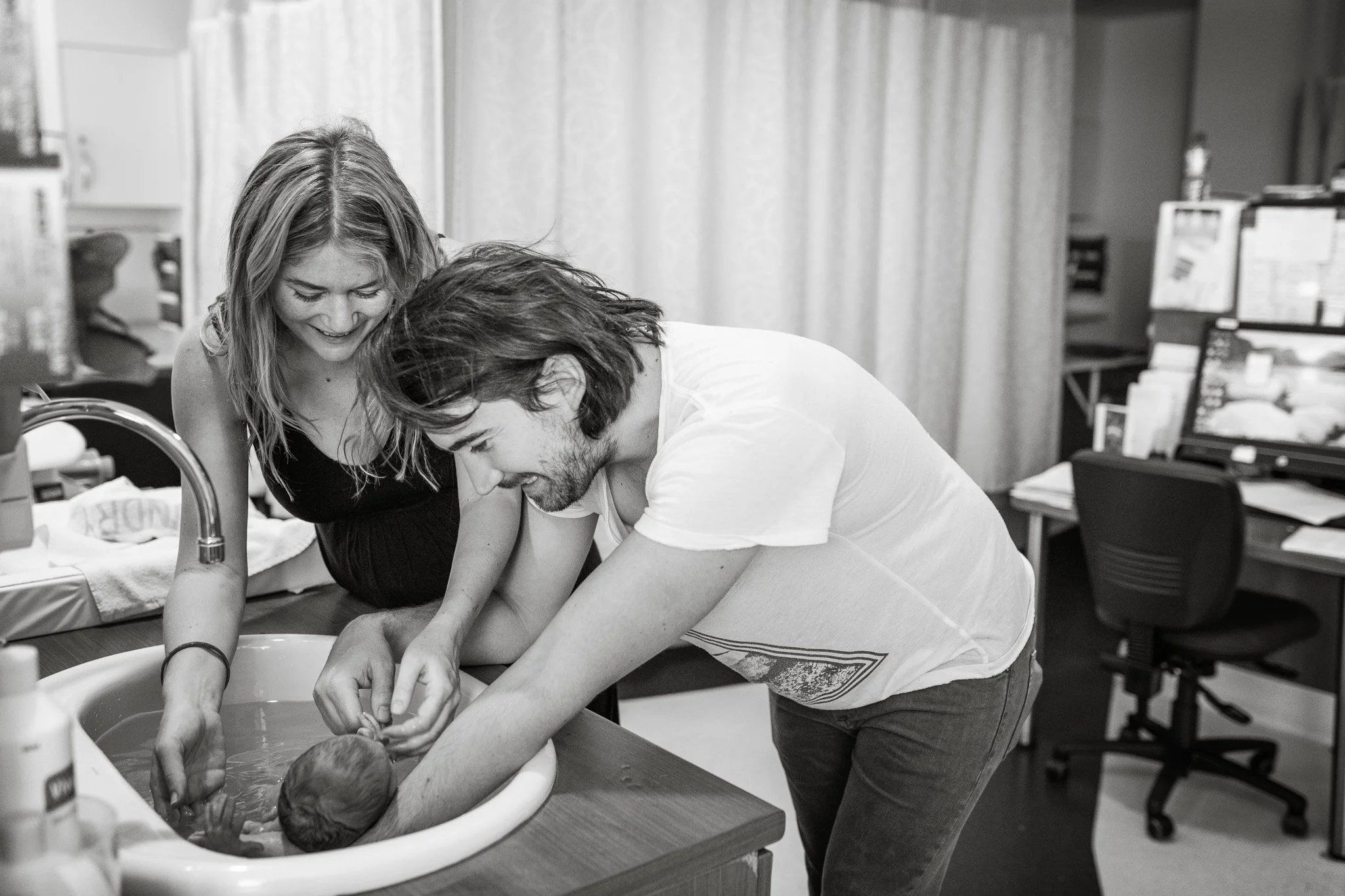 Parents gently bathing their premature newborn baby in the NICU at Melbourne's Royal Women's Hospital, captured during a volunteer photography session documenting early family moments and neonatal care.
