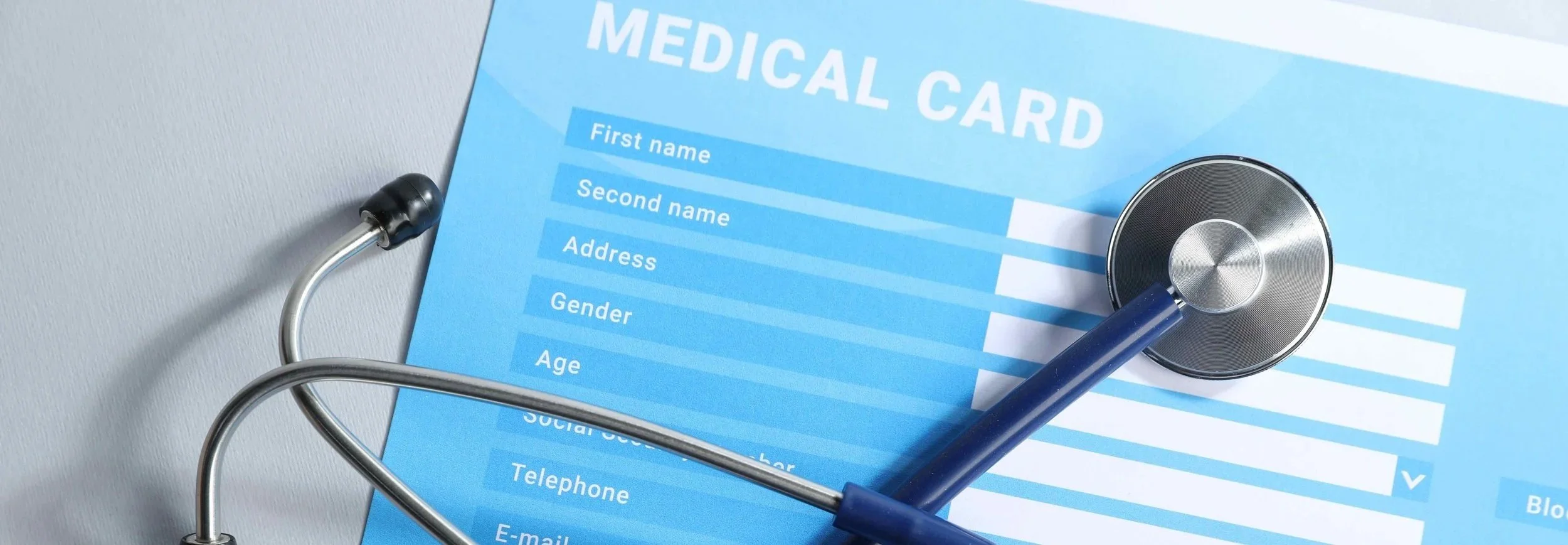 A stethoscope resting on a blue medical record or insurance card.