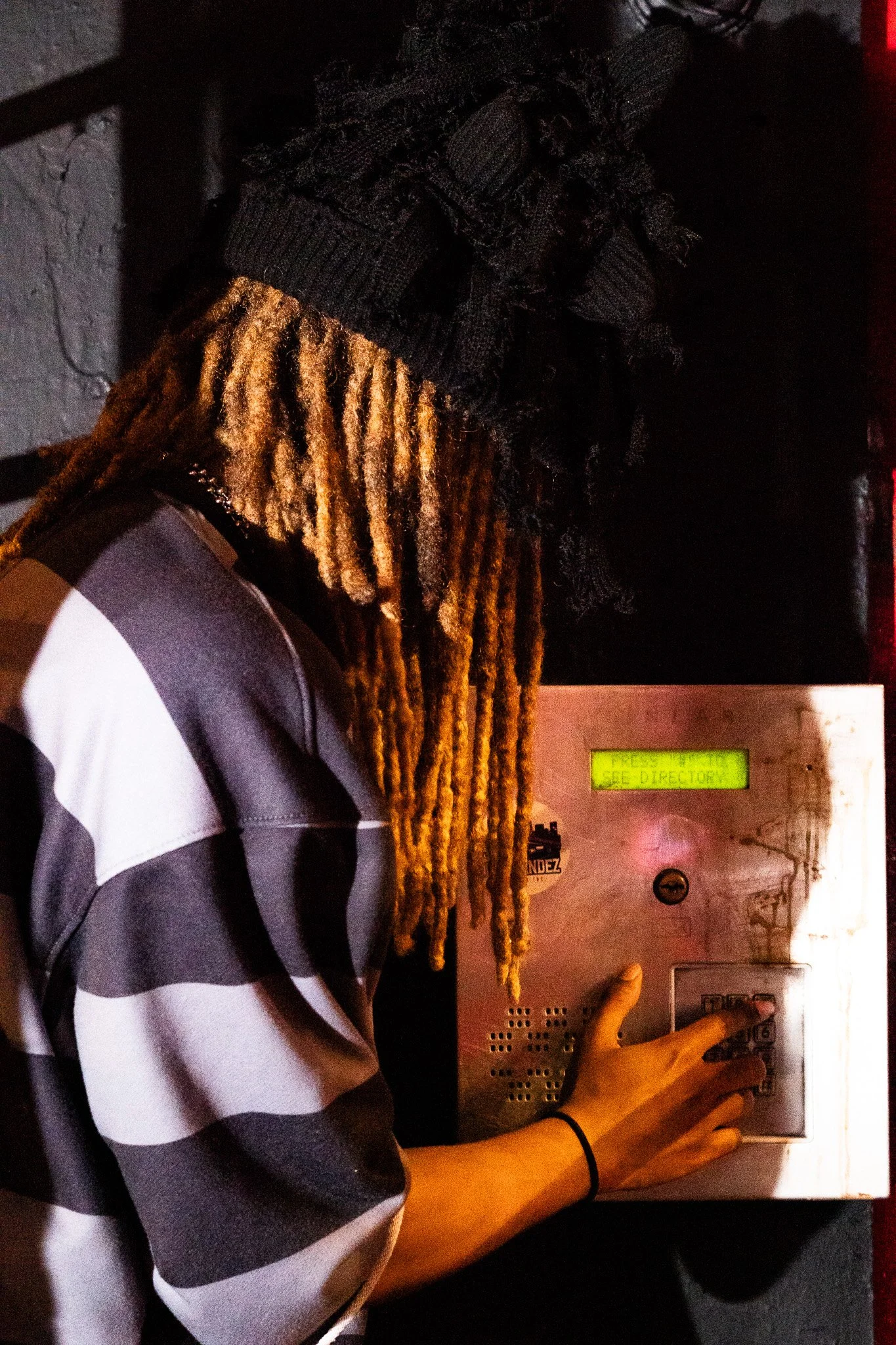 Person with long dreadlocks pressing a button on an elevator control panel.