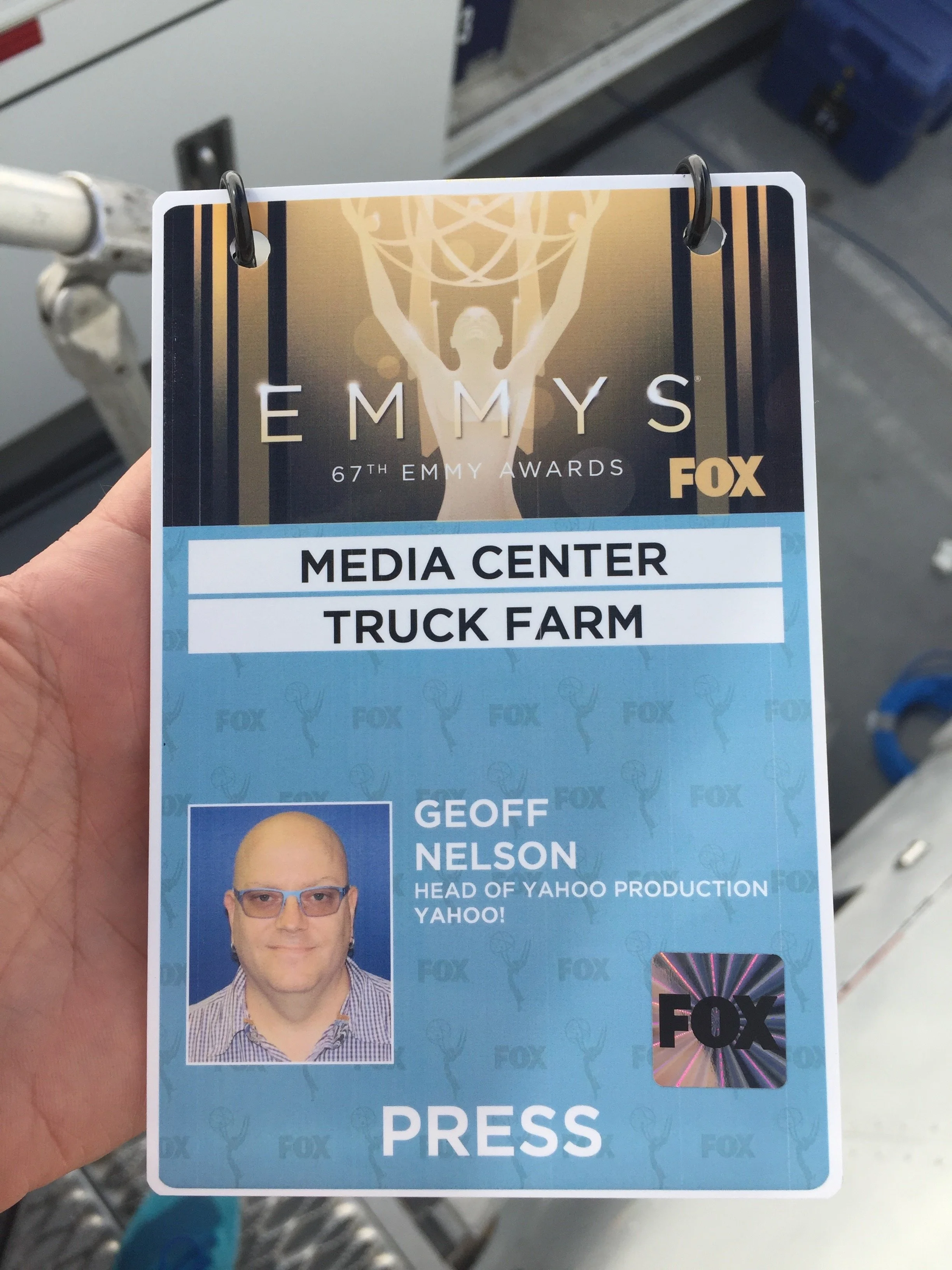 ID badge for Emmy Awards, Fox, with photo of presenter Geoff Nelson, labeled head of Yahoo production, held in front of a store aisle with shelves and a shopping cart in background.