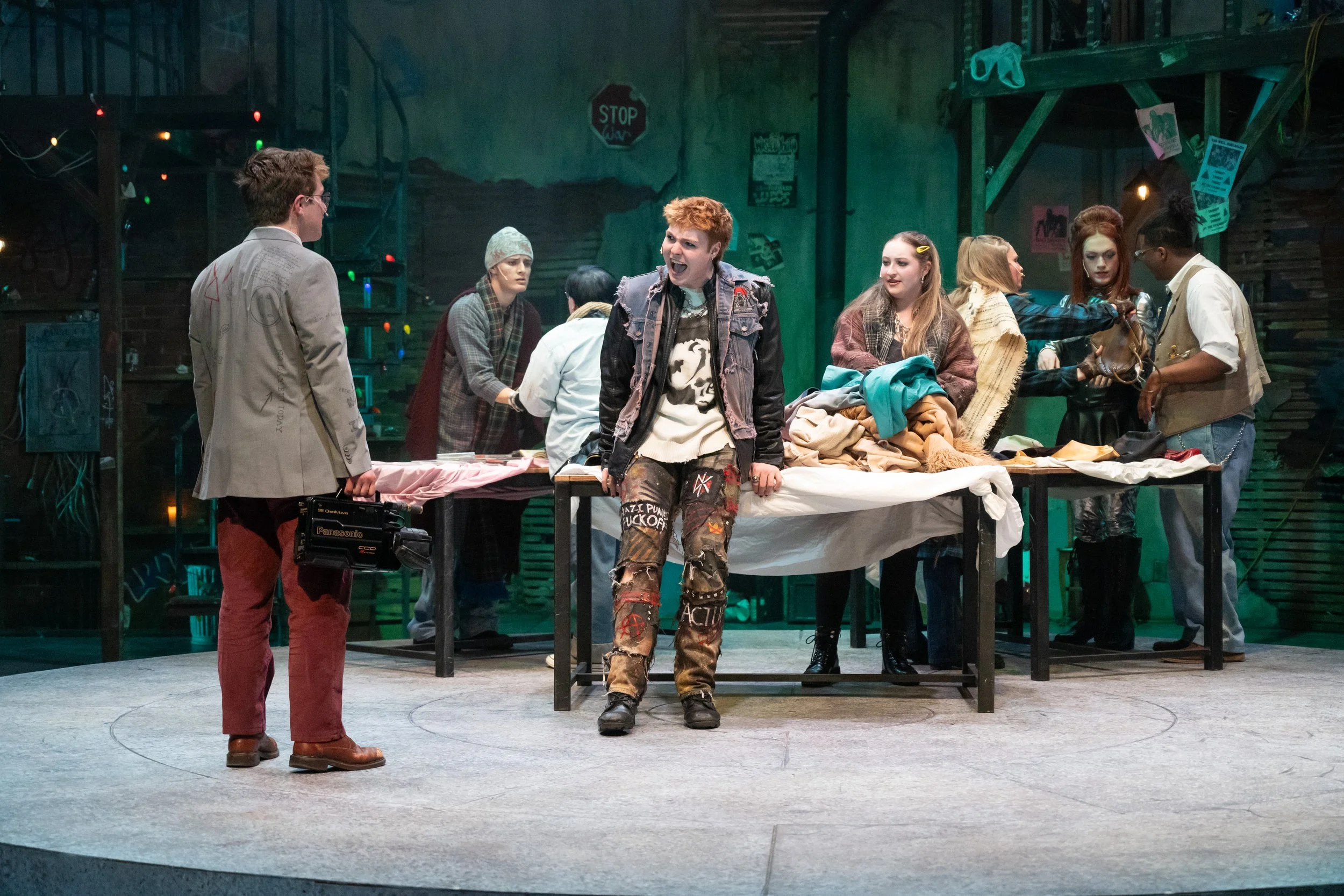 Roger (Nathan Adams) argues with Mark (Ryan Terry) on the street in front of the vendors