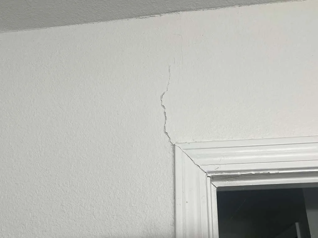 Cracked wall near ceiling and doorway trim.