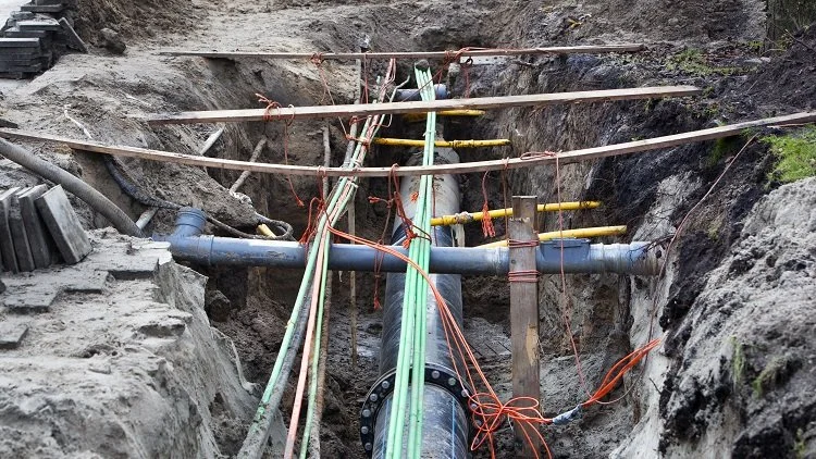 Construction site with large underground pipes and scattered equipment.