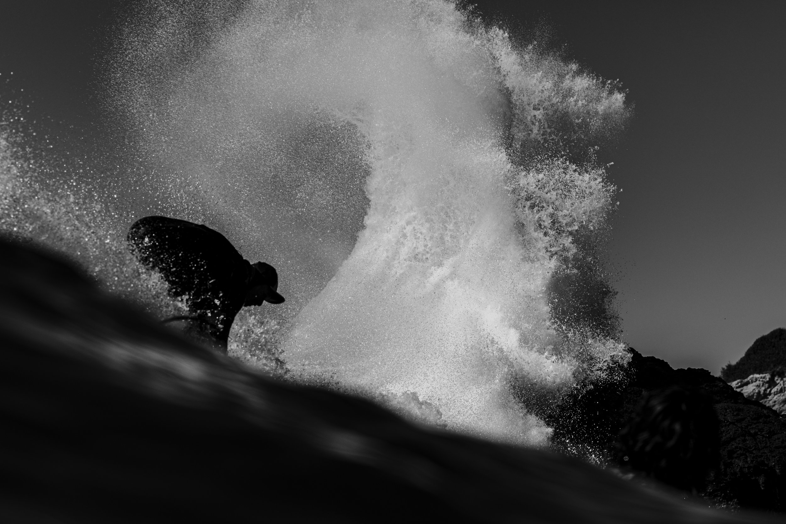A person in a wetsuit riding a jet ski on the water, creating a large splash and spray.