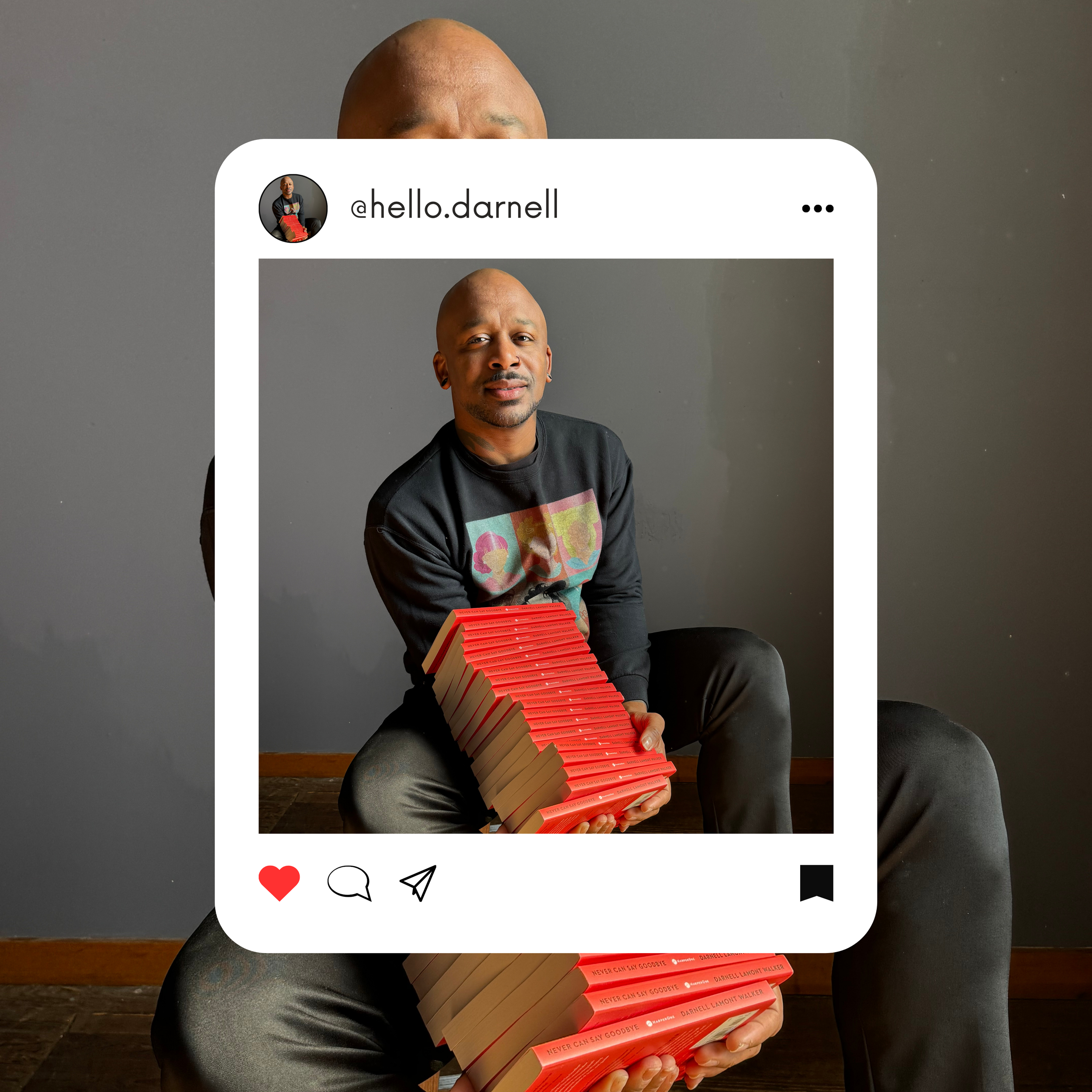 A man with a shaved head and tattoos on his arms, sitting with crossed legs, holding a stack of red books titled 'Never Can Say Goodbye' by Darnell Lamont Walker, in front of a gray wall.