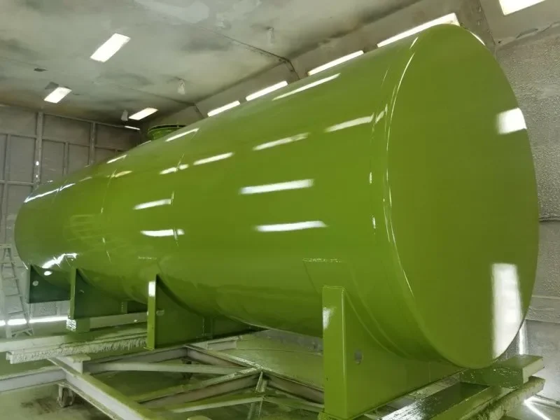 Large, horizontal, green cylindrical tank inside an industrial facility.