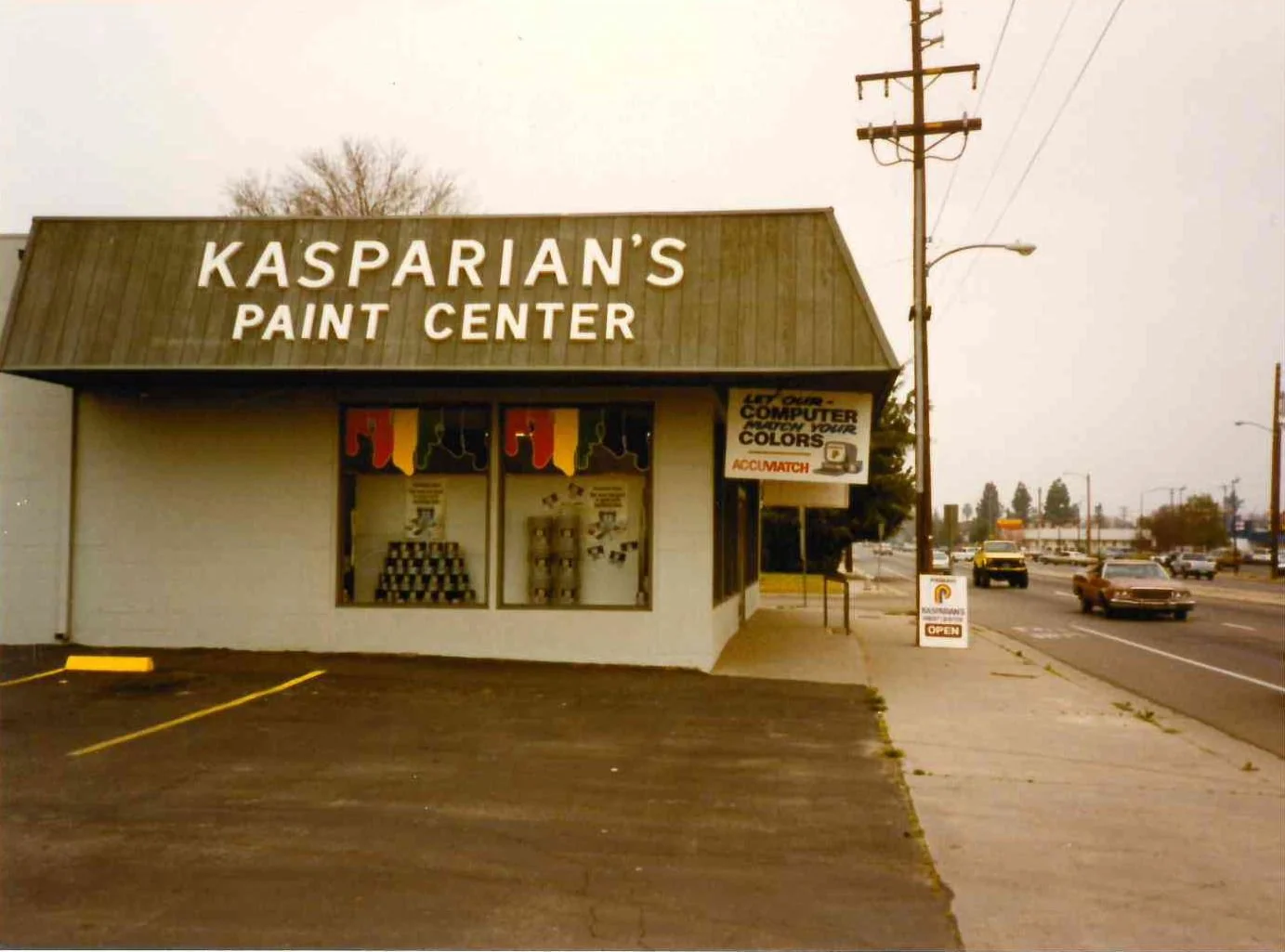 Historic exterior of Kasparian's Paint Center store: a brown and white building, large window displays, and street parking. Signage for paint supplies and computer color matching service is visible.