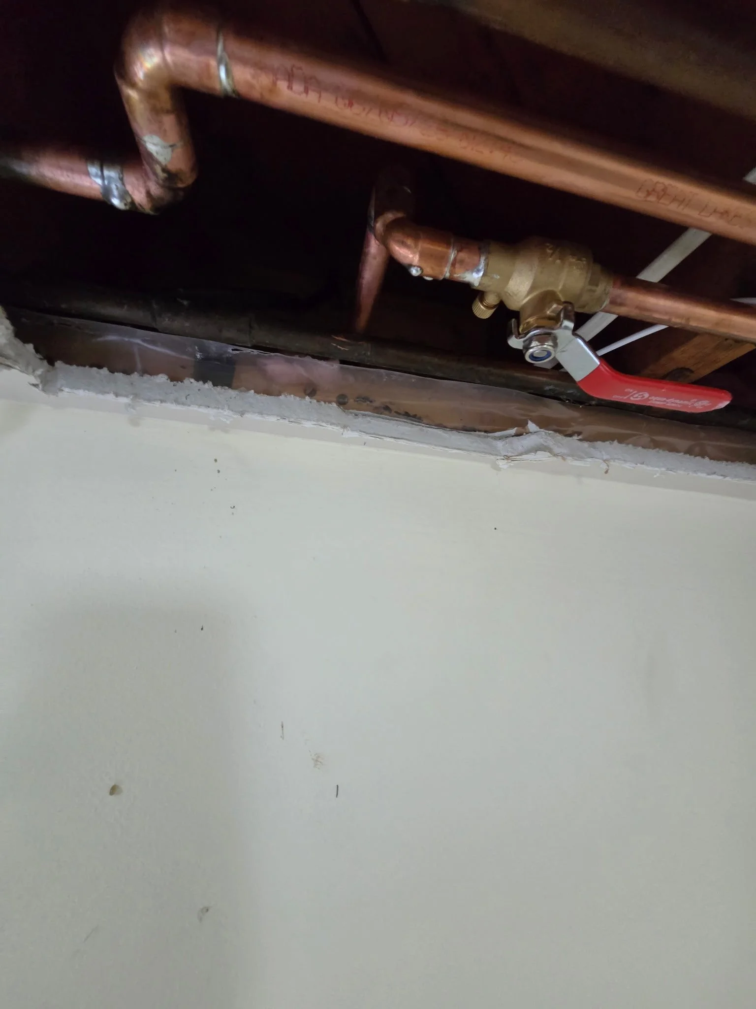 Copper plumbing pipes with shut-off valve in a ceiling space.