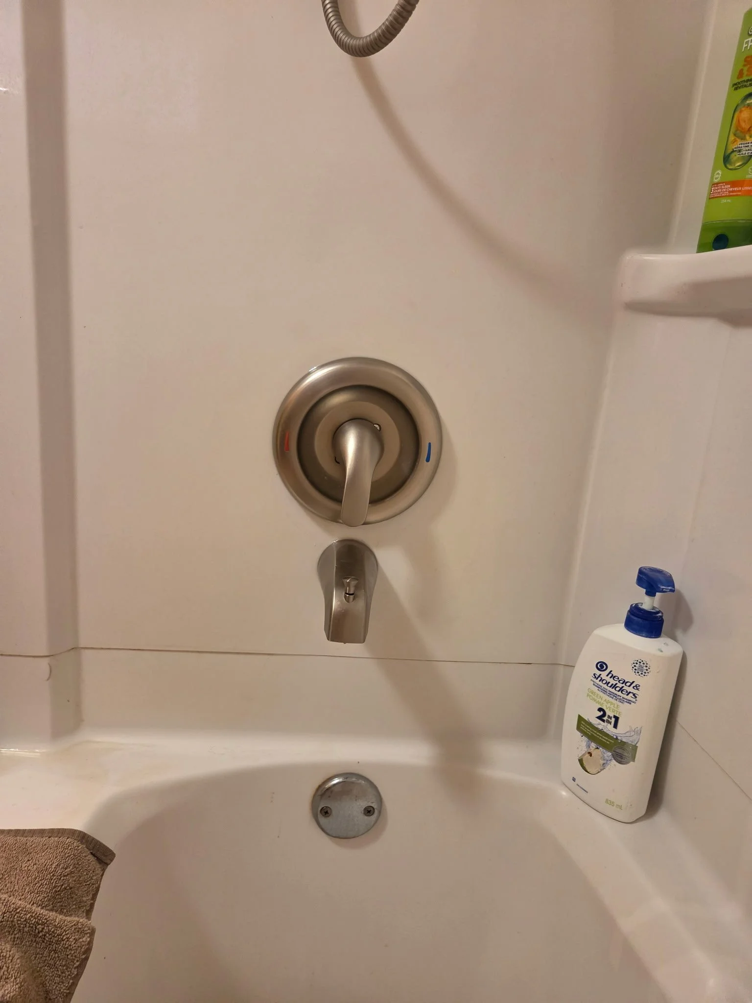 Inside a bathtub with a faucet, a soap dispenser on the right, and a towel in the lower left corner.