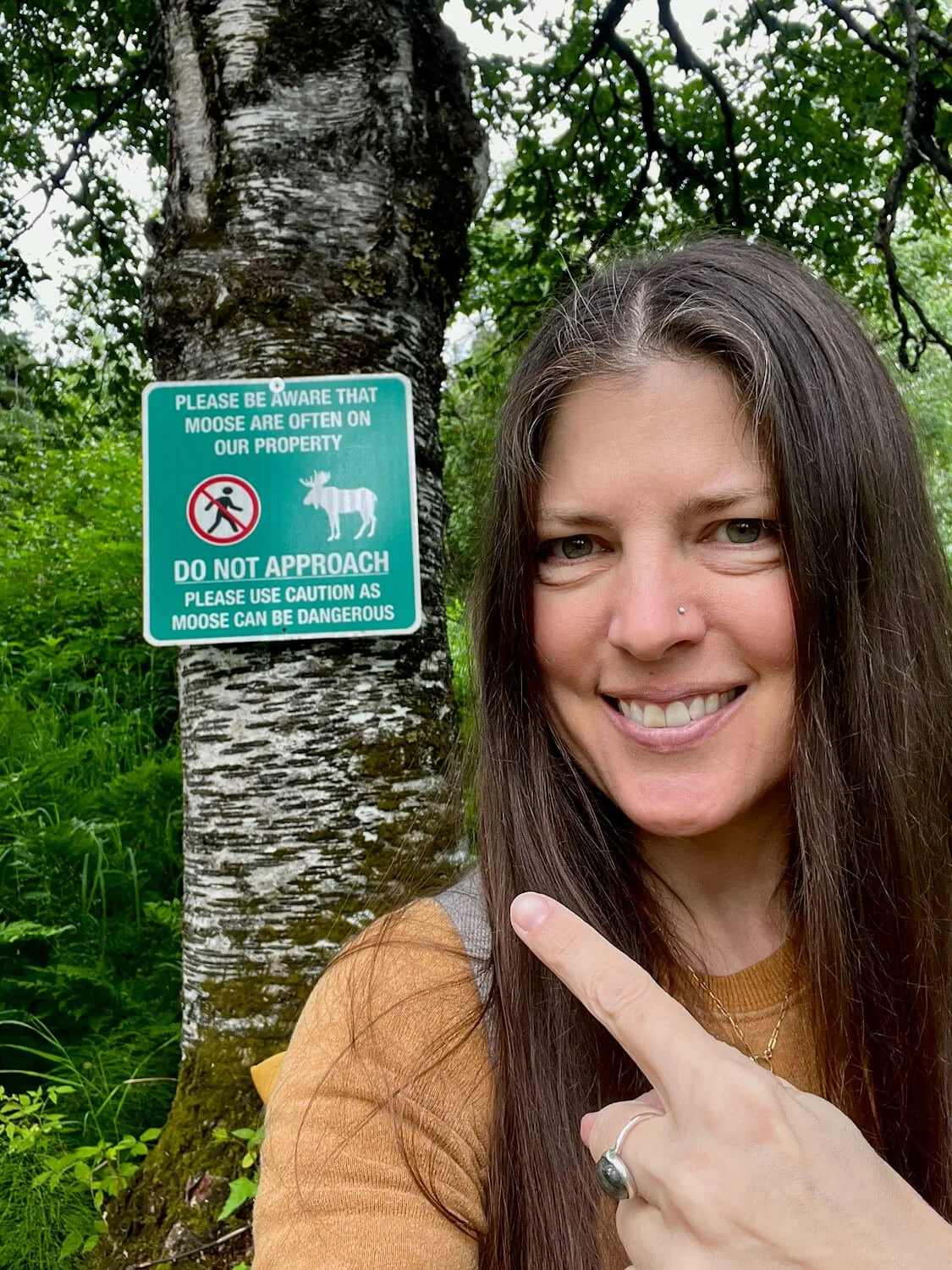 Kristi pointing to a sign that warns people not to approach the moose