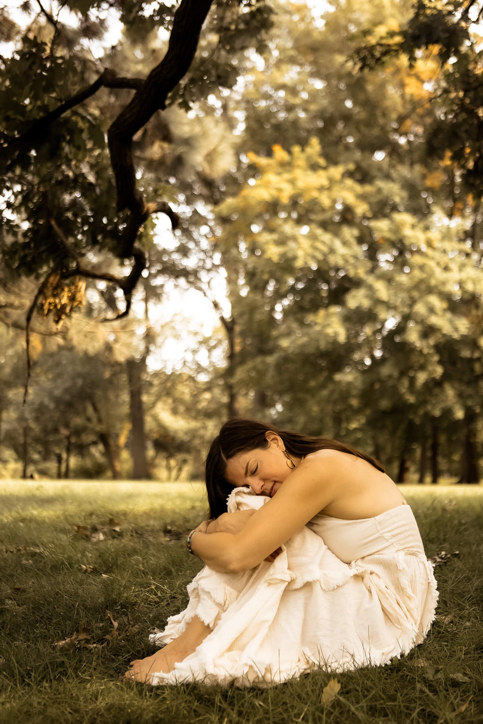 Kristi hugging her knees while sitting in the grass
