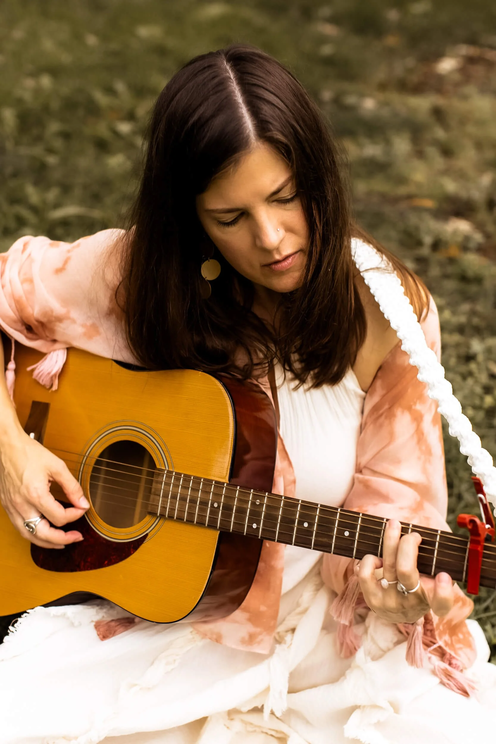 Kristi sitting in a field playing her guitar (2 of 4)