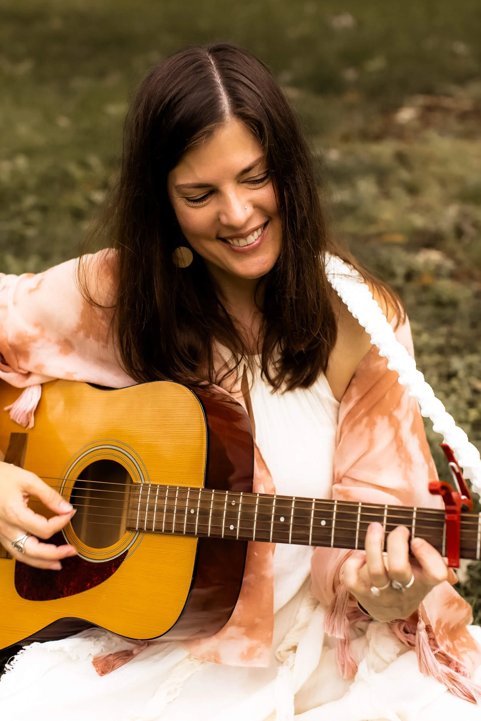 Kristi sitting in a field playing her guitar (3 of 4)