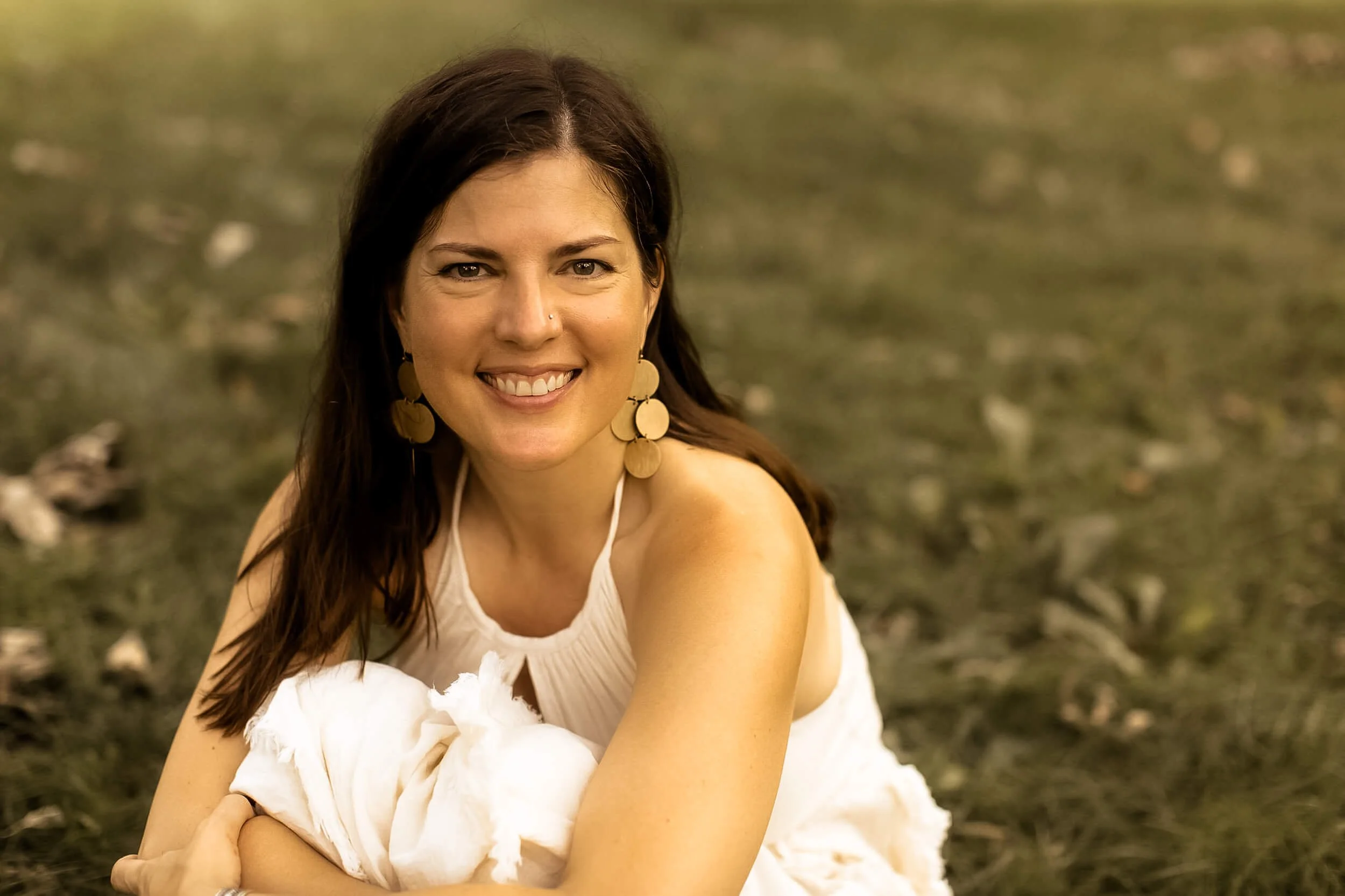 Kristi sitting on the ground and smiling at the camera