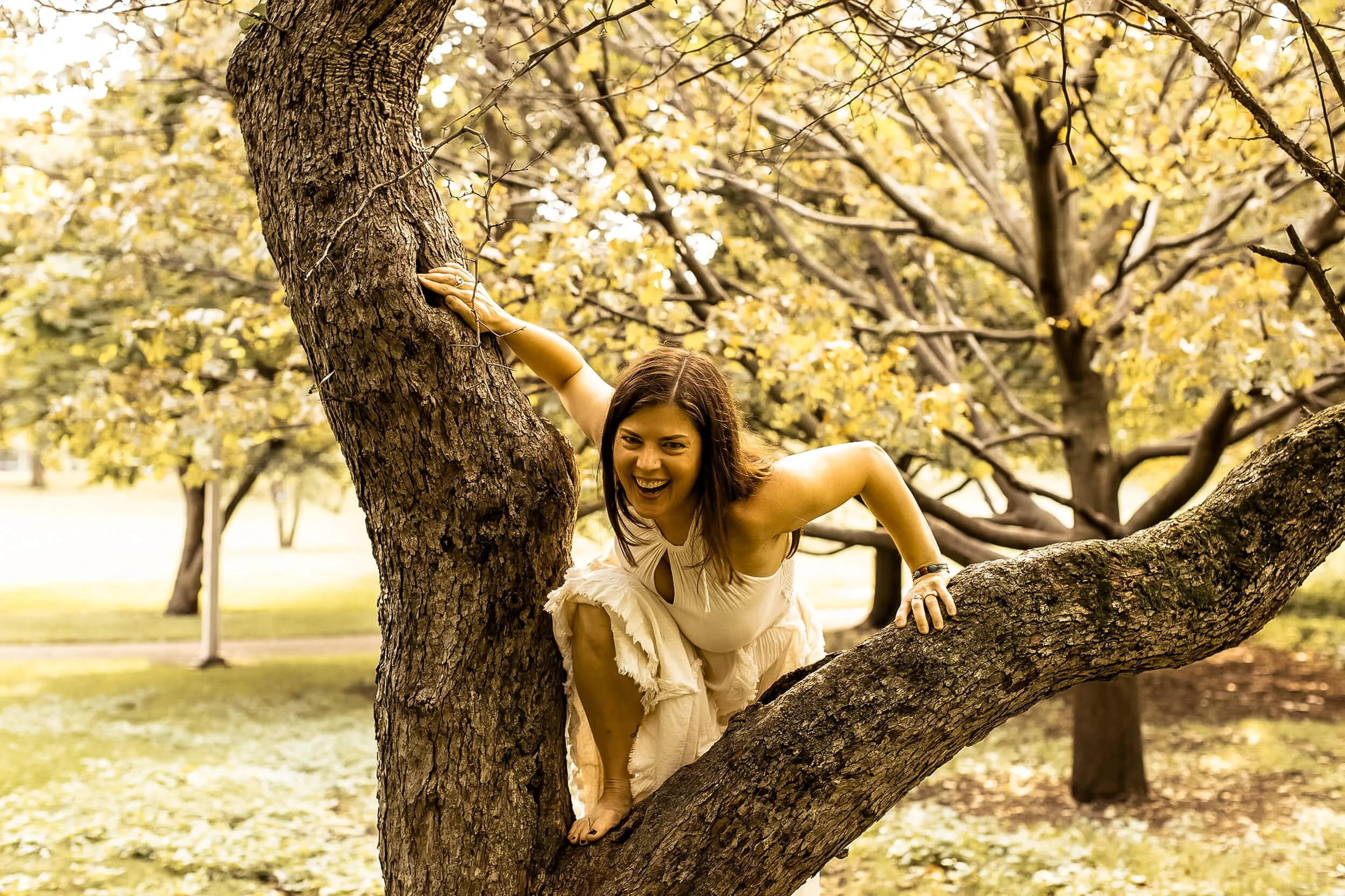 Kristi climbing a tree while wearing an earth goddess dress