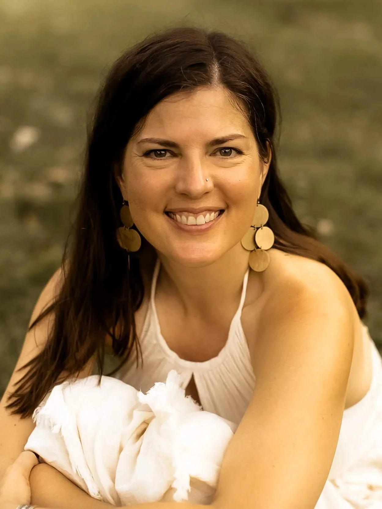 Kristi Amdahl sitting on the ground and smiling at the camera
