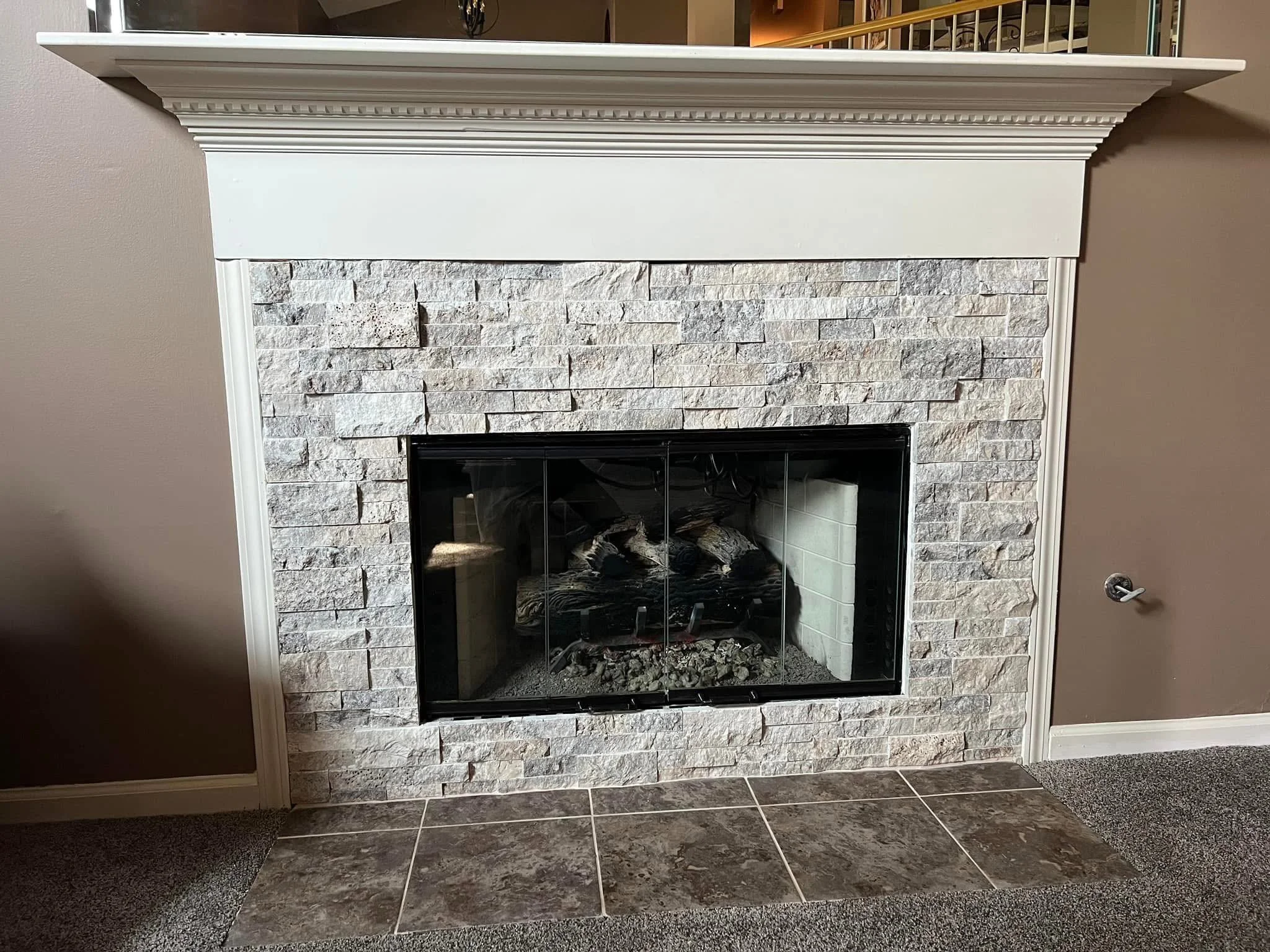 White fireplace with a stone brick surround and a white mantel in a living room.