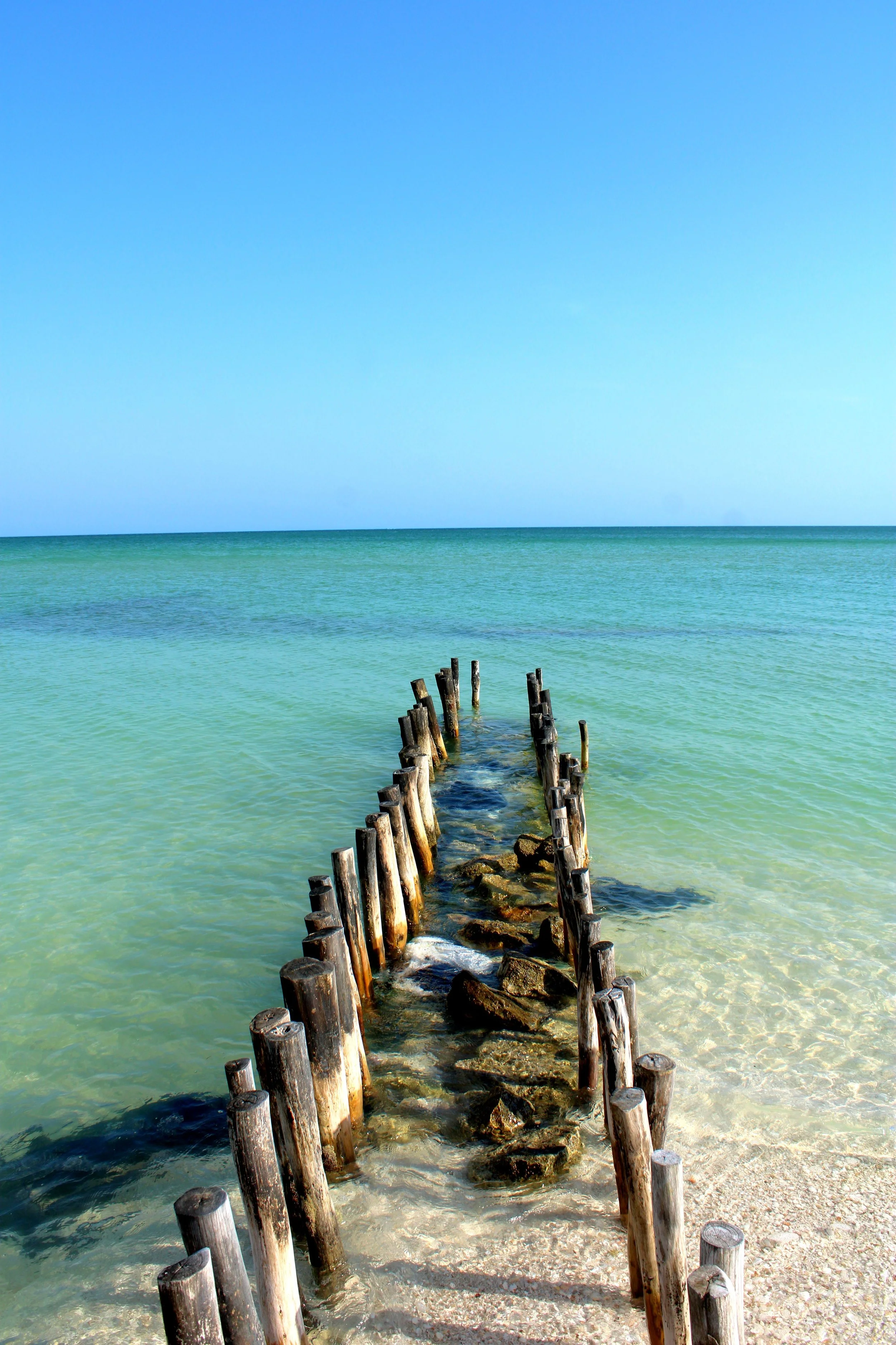 Puente de madera en las aguas del mar con cielo azul claro.