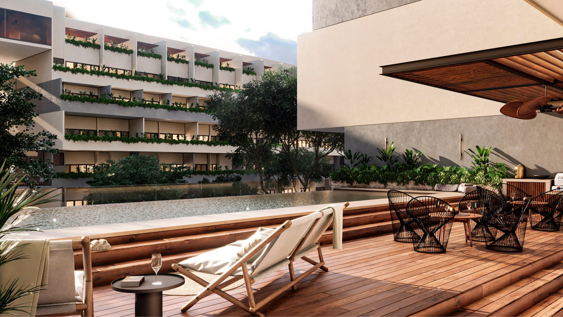 Terraza moderna con muebles de madera, sillas de mimbre negras, área de descanso con tumbonas y plantas verdes, vista a un edificio con balcones con plantas, cielo nublado