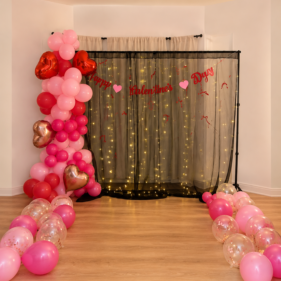 Valentine's Day celebration decor with pink and red balloons, heart-shaped balloons, fairy lights, and a banner that says "Happy Valentine's Day" in front of a sheer curtain.