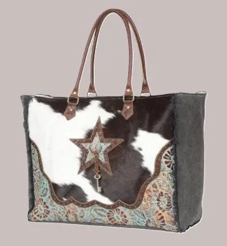 A tote bag made from cowhide with decorative leather accents and a star-shaped keychain attached to the handle.