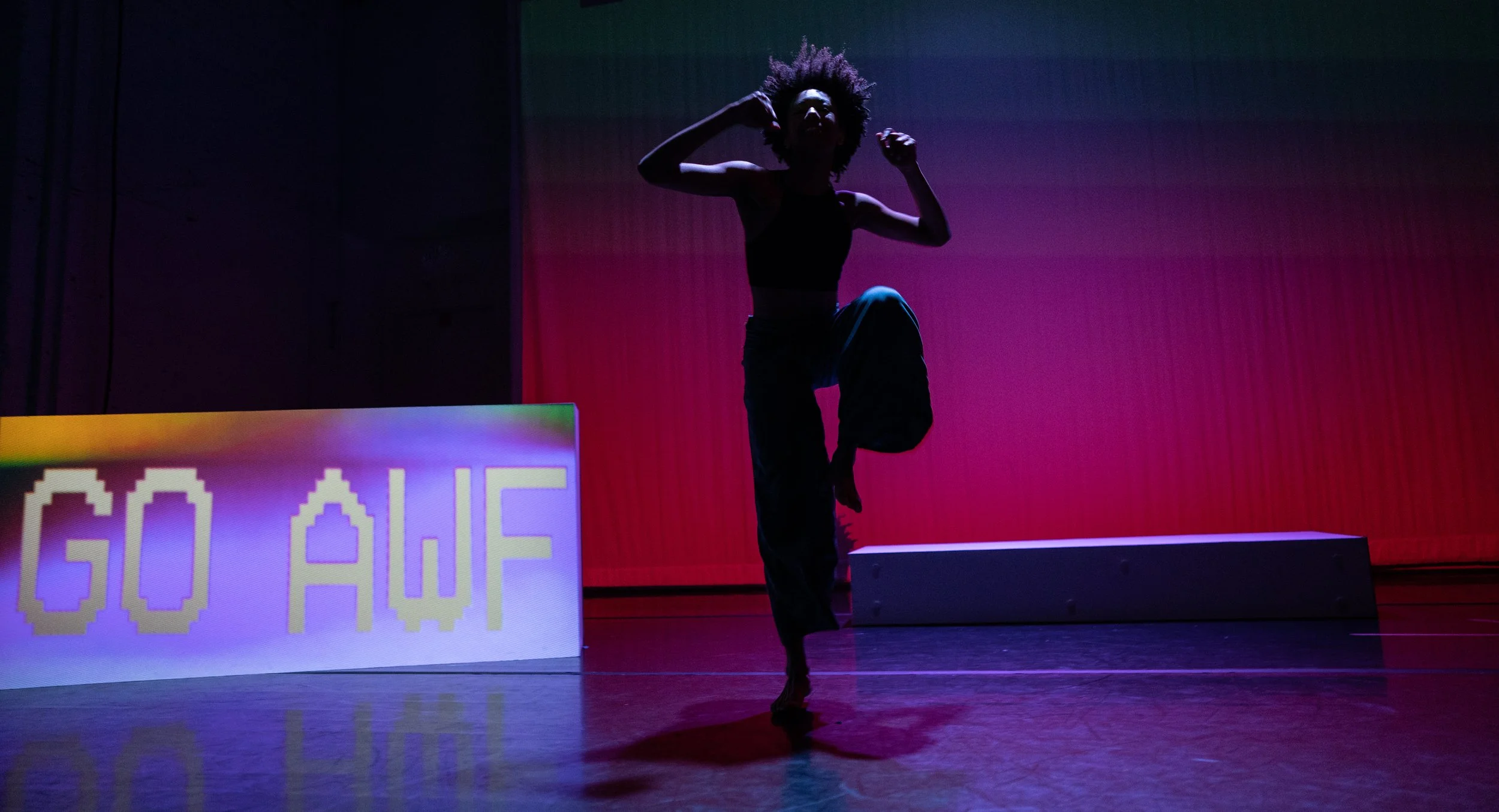 A silhouette of a person with curly hair dancing on stage with colorful lighting, with a digital display showing the temperature as 50°F in the foreground.