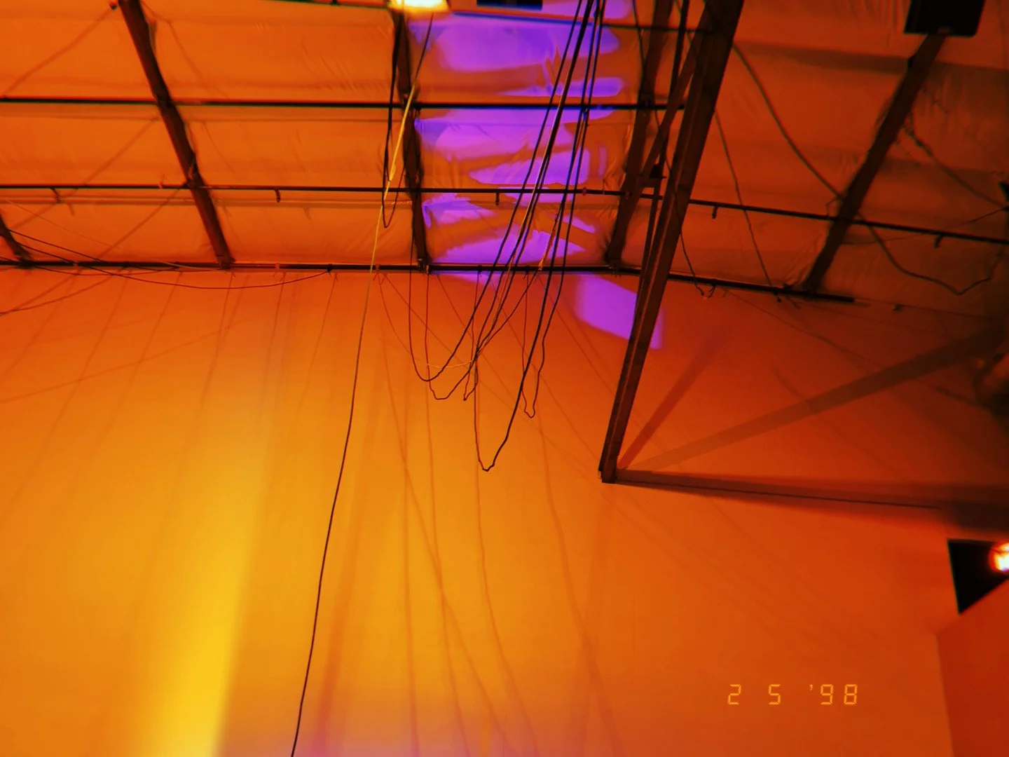 Ceiling with orange lighting, visible wires, and a metal structure with purple accent lights.