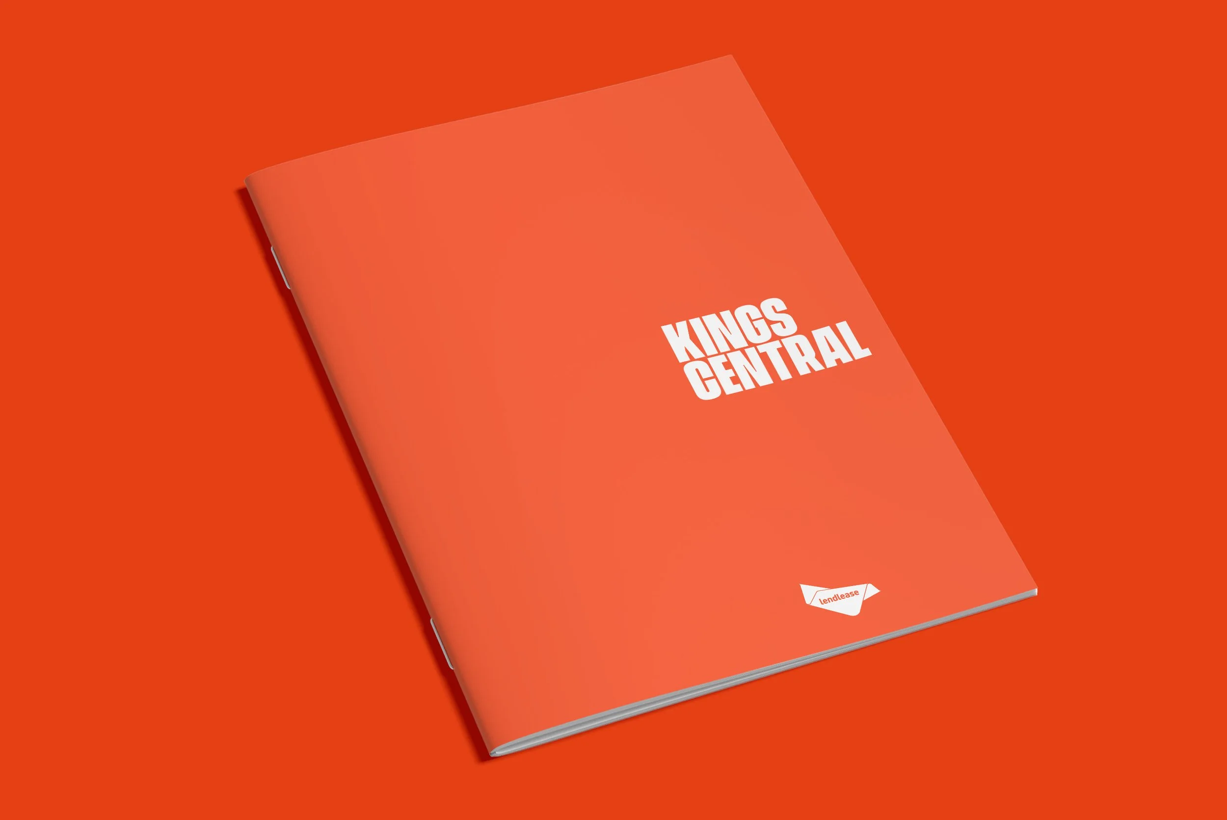 A red notebook with white text that says 'KINGS CENTRAL' on the cover, placed on an orange background.