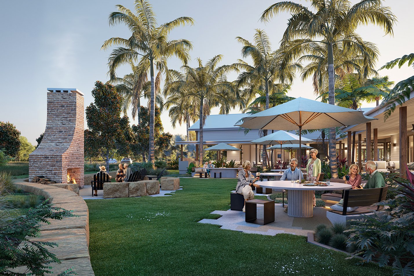 Outdoor gathering with people sitting under umbrellas, enjoying drinks near a round table, with a brick fireplace and tall palm trees in the background, on a sunny day.