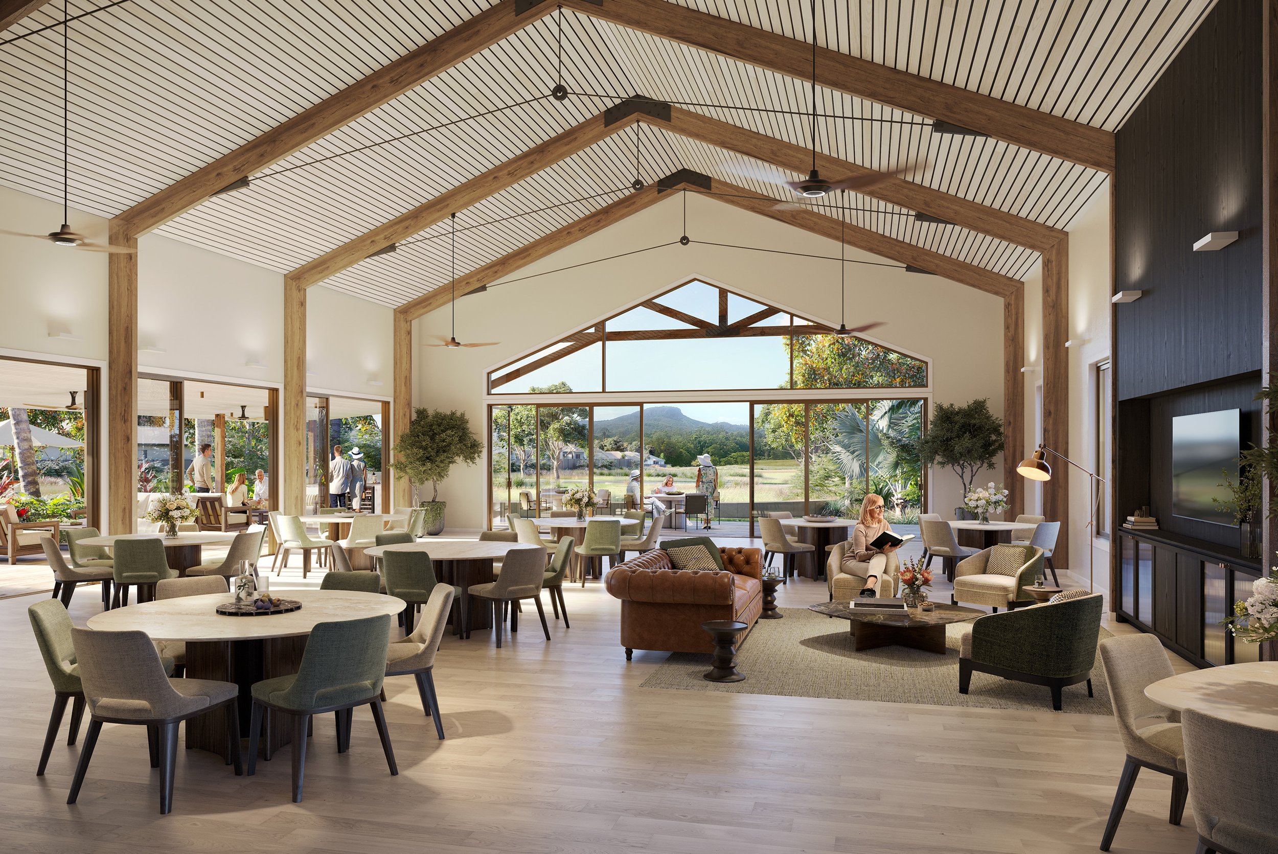 A spacious indoor lounge area with high vaulted ceiling supported by wooden beams, large windows revealing an outdoor landscape, and people sitting and standing enjoying the space.