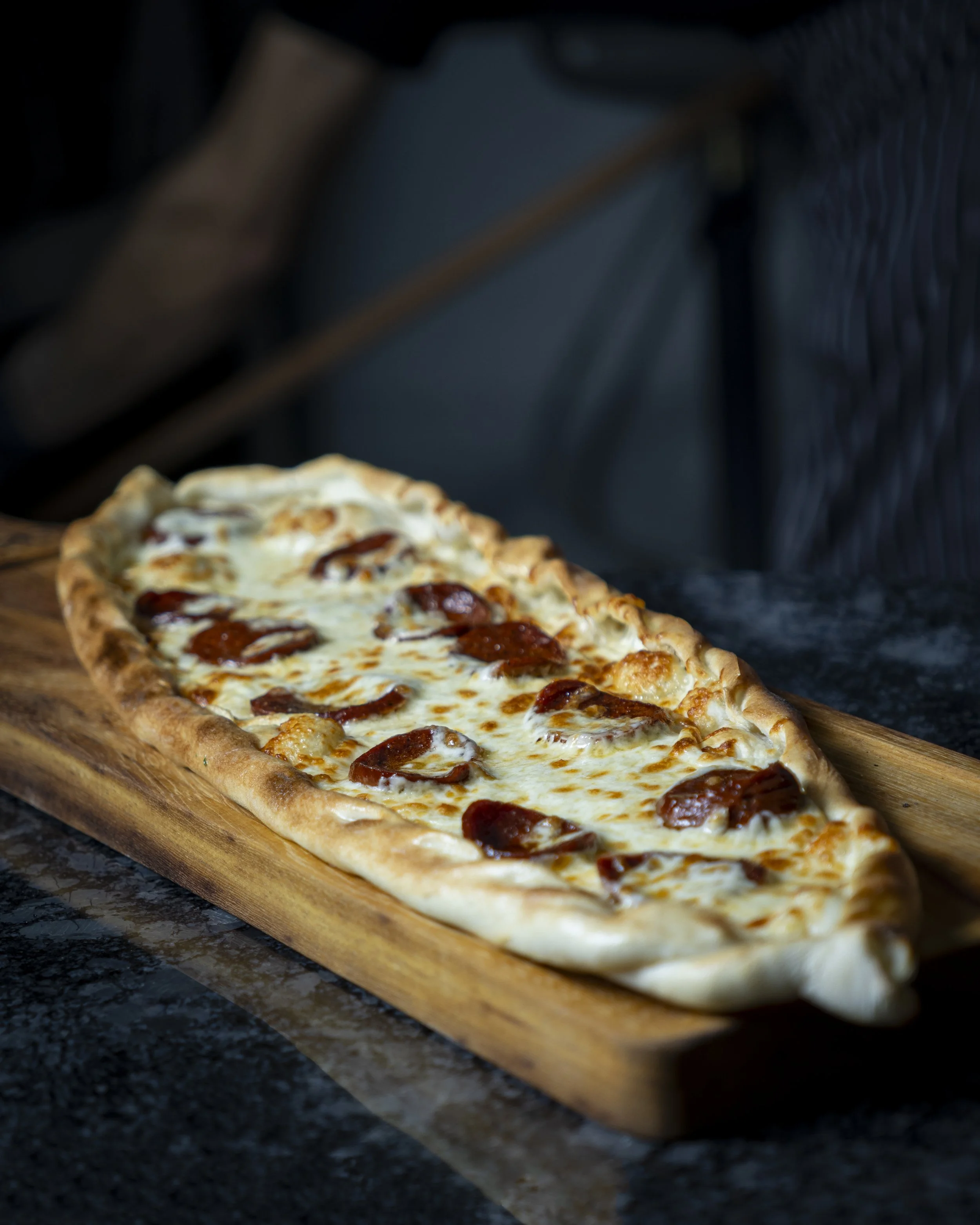 A slice of pepperoni pizza on a wooden serving board