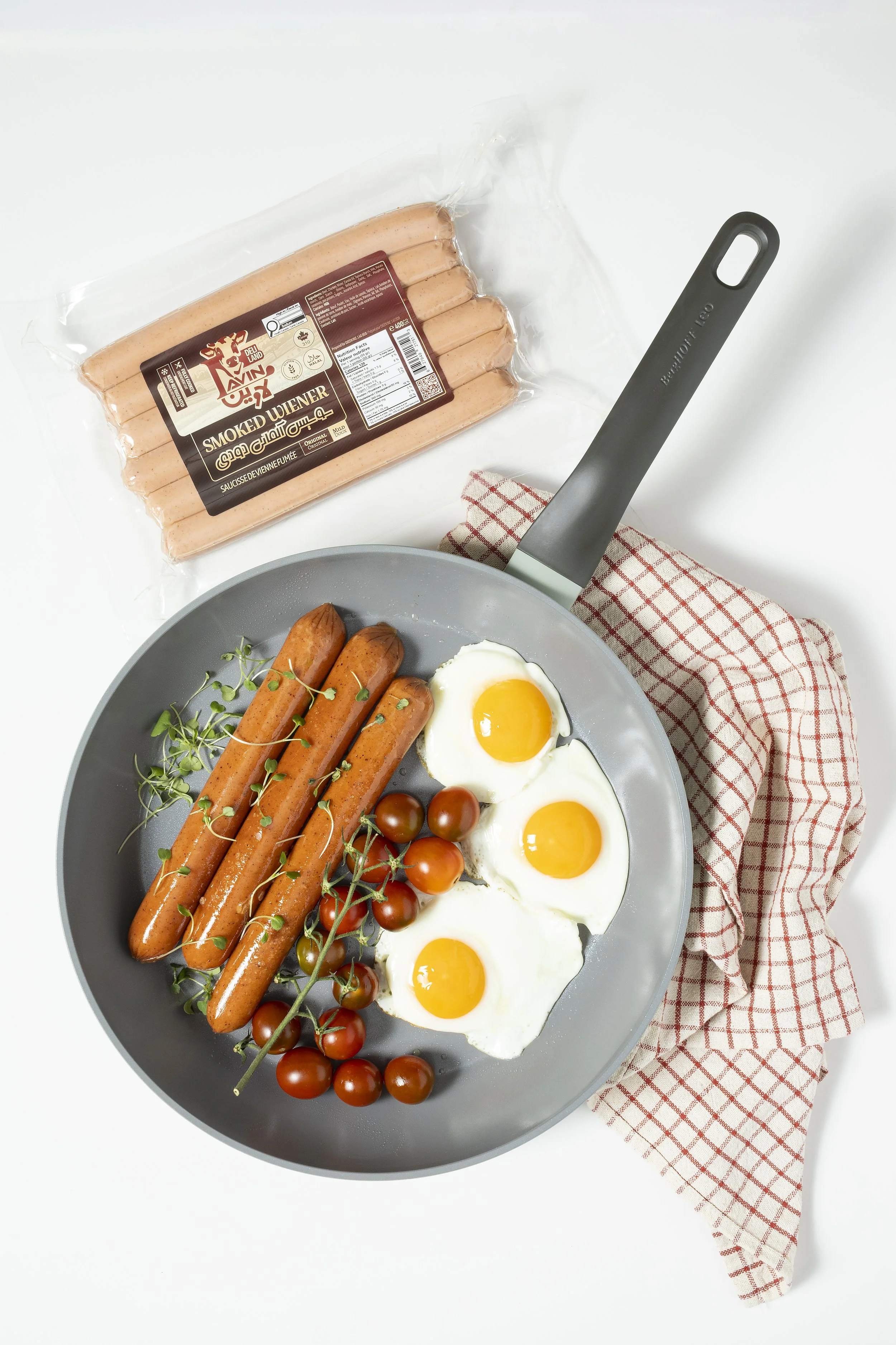 Commercial food photography featuring a styled breakfast with eggs, sausages, and packaged food product.
