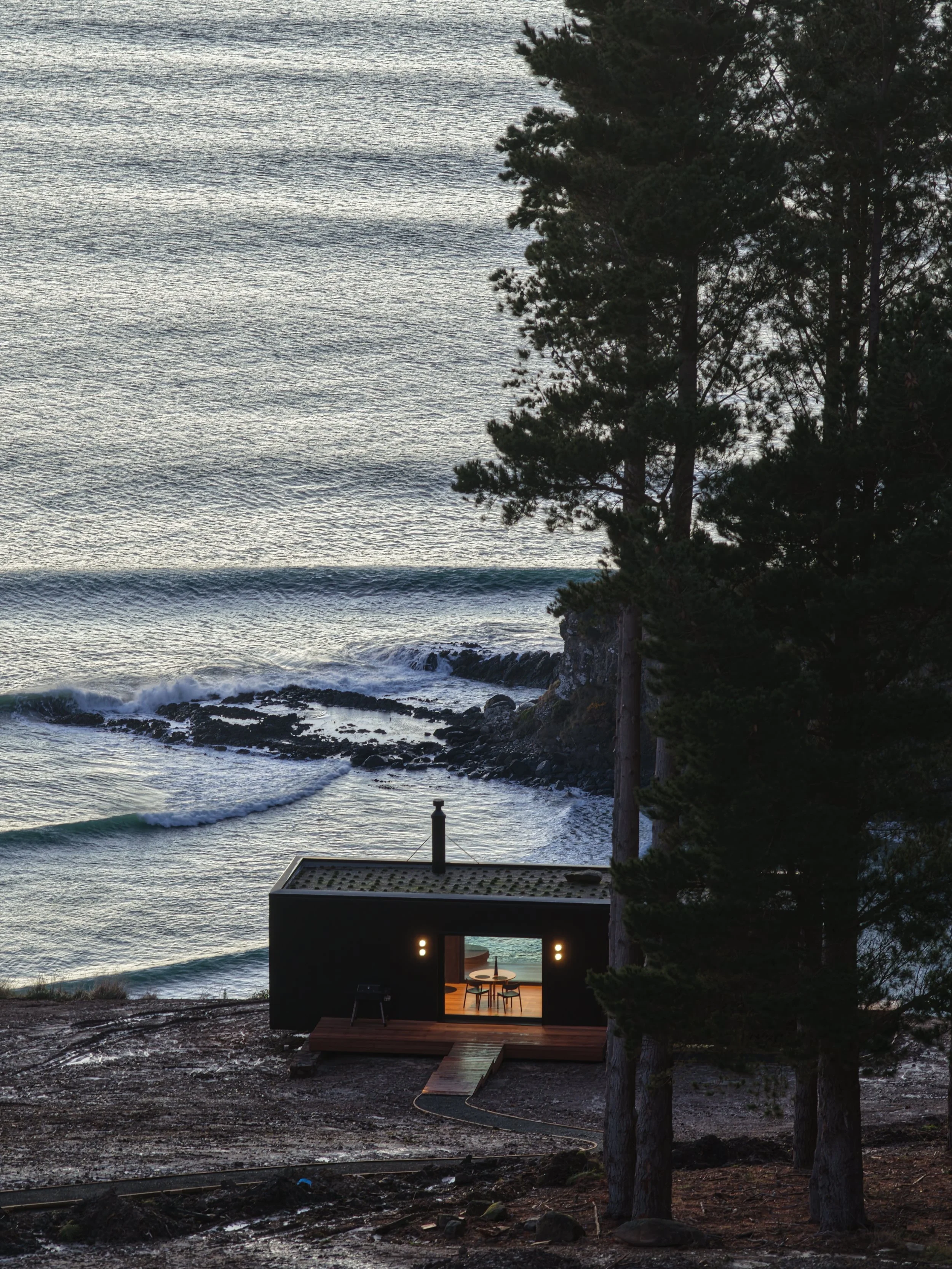 A clifftop cabin over looking the historic Māpoutahi Pā with surf waves in the background.